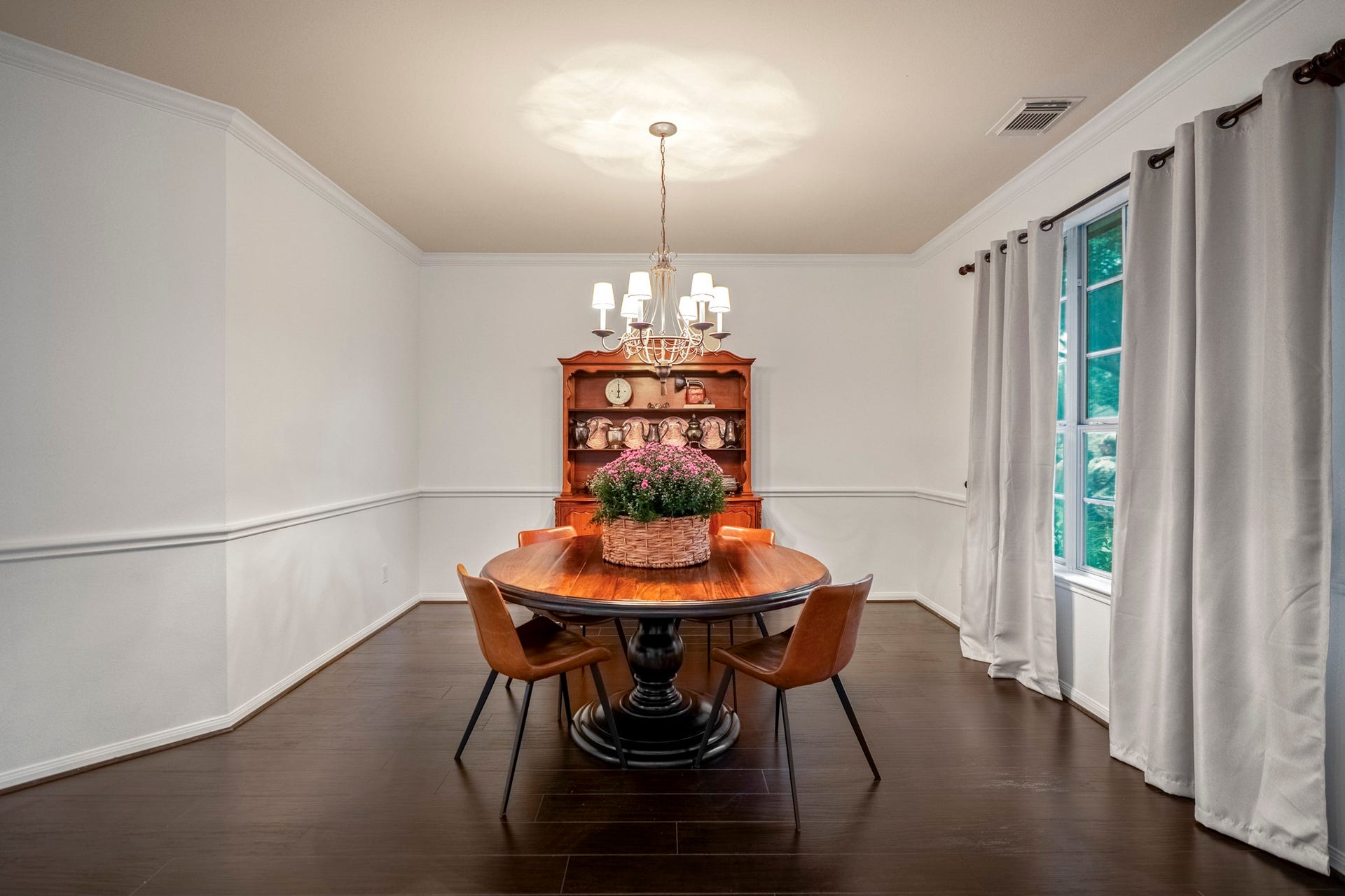 The formal dining room offers an airy atmosphere, while the rich, dark wood look flooring offers a striking, high-end contrast to the crisp white trim and neutral walls.