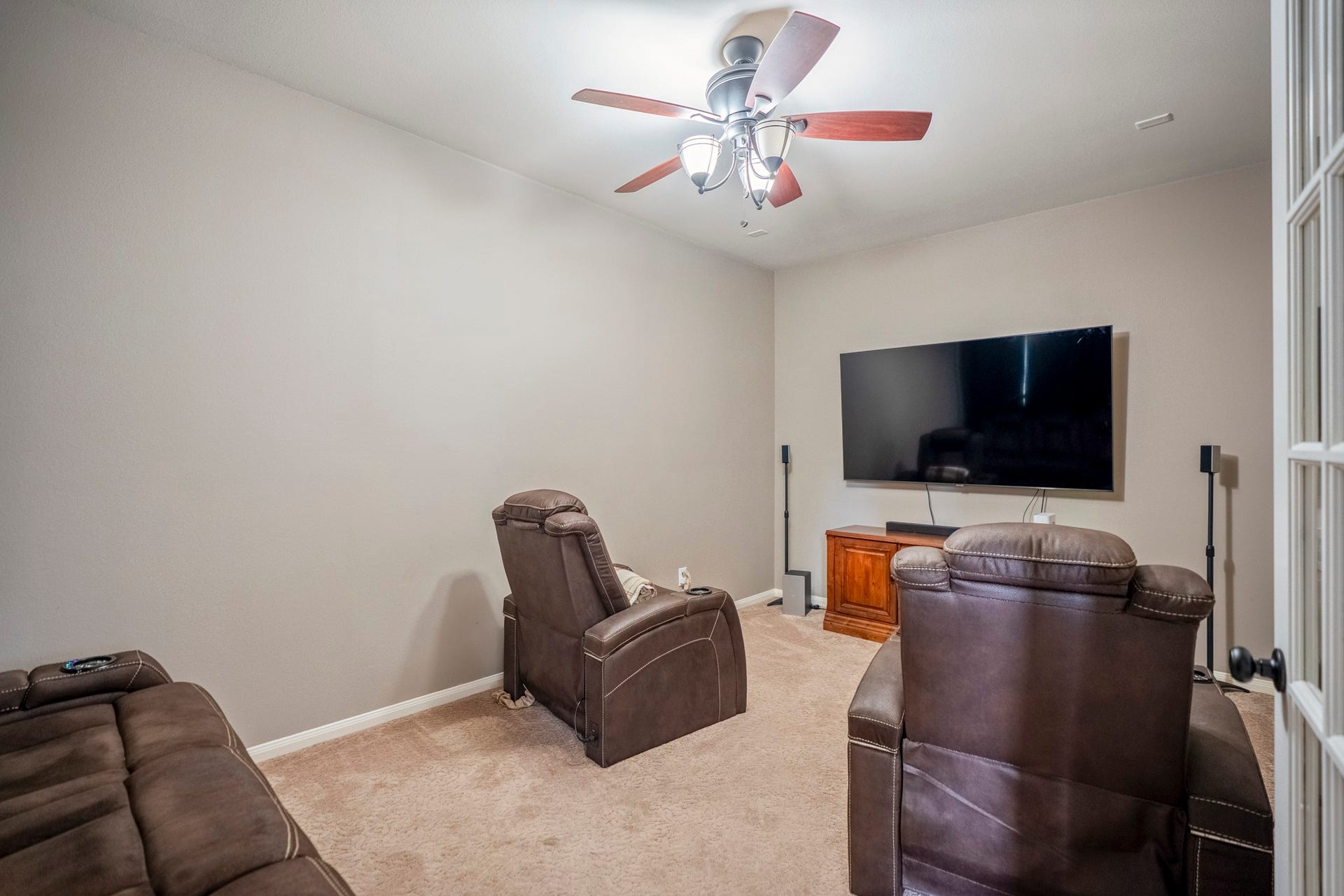 The downstairs media room offers a place to retreat and watch your favorite show, with plush carpeting and an updated ceiling fan.
