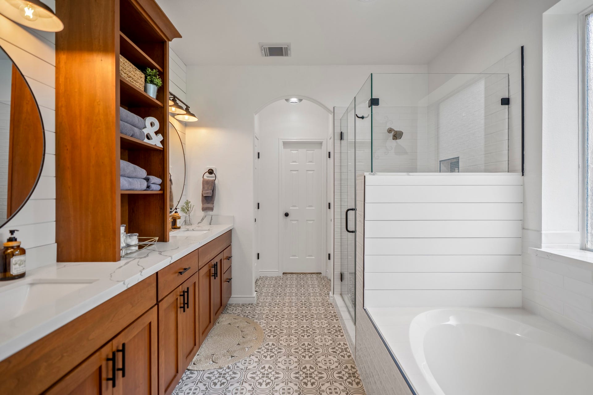 Beautiful updated en-suite bathroom features updated flooring, cabinetry and lighting, soaking tub, and glass enclosed shower.