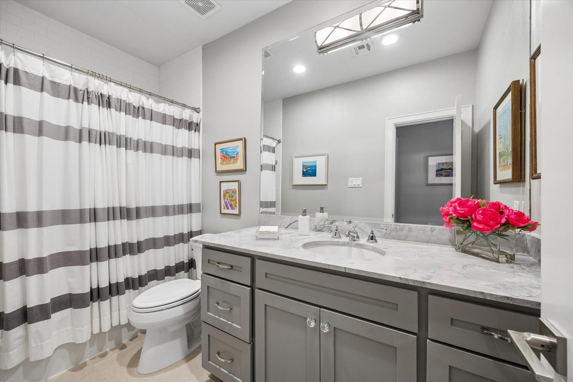 BATHROOM: Renovated secondary bathroom features marble countertops, custom cabinetry, contemporary lighting and a tub/shower combination with subway tile surround and shampoo shelf.
