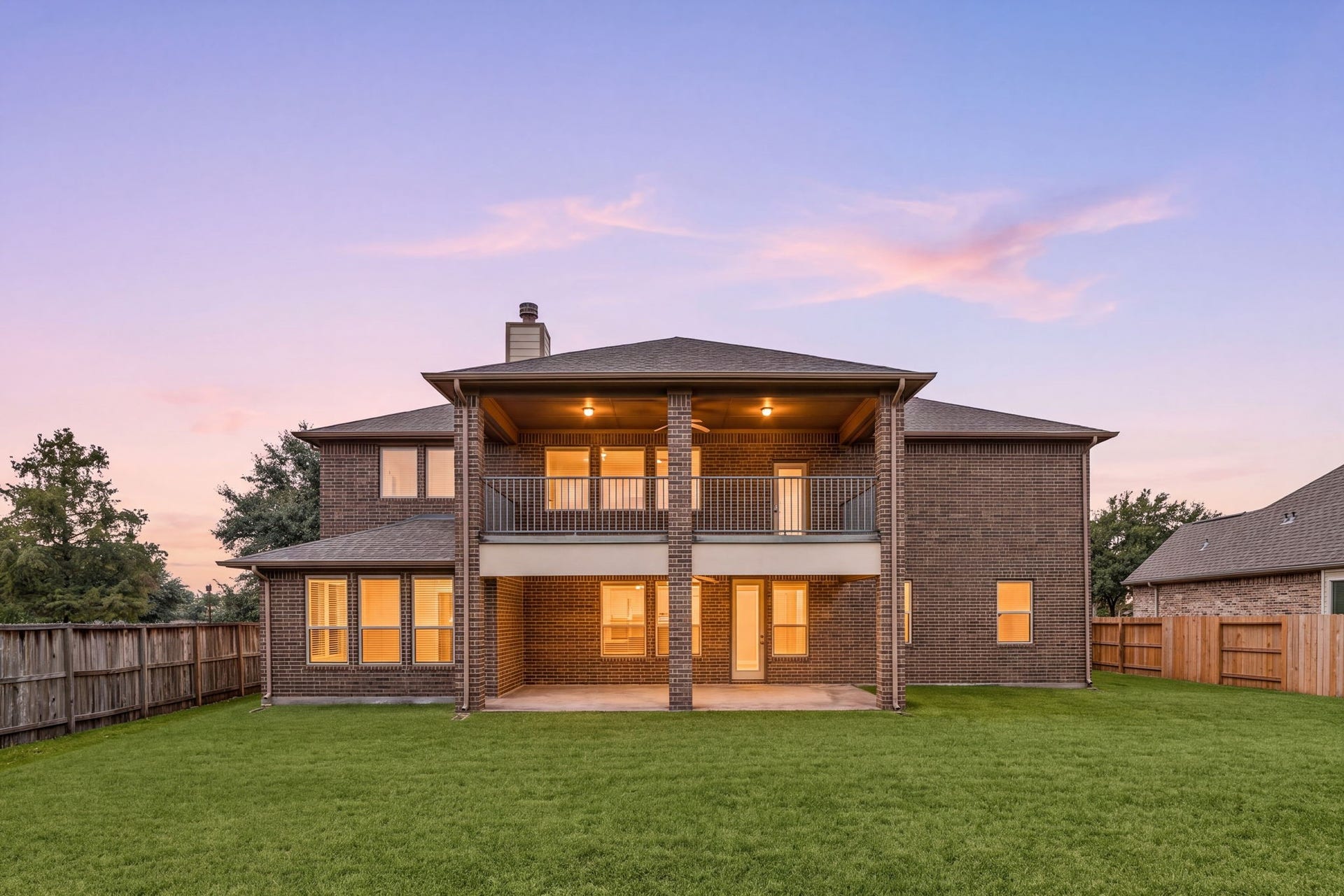 26306 Sunny Springs Lane, Cypress, TX 77433 Stunning twilight view showcases the homes impressive rear elevation, expansive covered second-floor deck, covered ground-level patio, and large backyardan exceptional setup for outdoor living and entertaining.