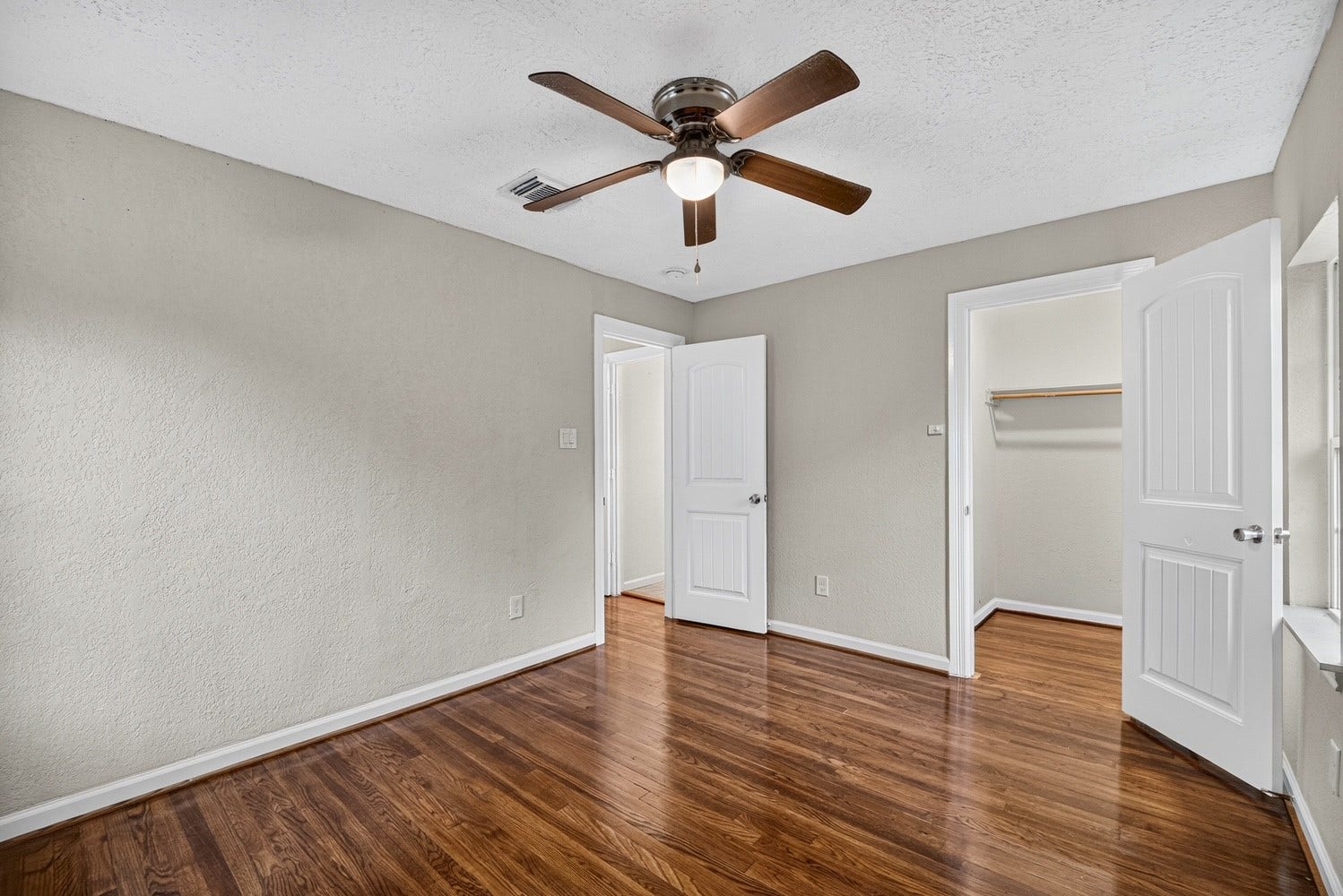 Bedroom 3 with ceiling fan and refinished original wood flooring.