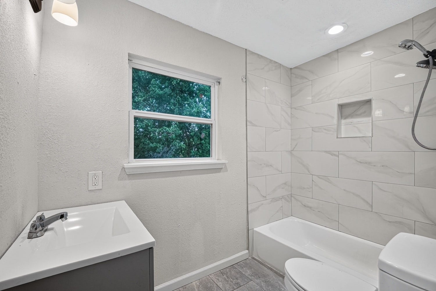 Recently remodeled full bath/shower combo with tile flooring and solid surface countertop.