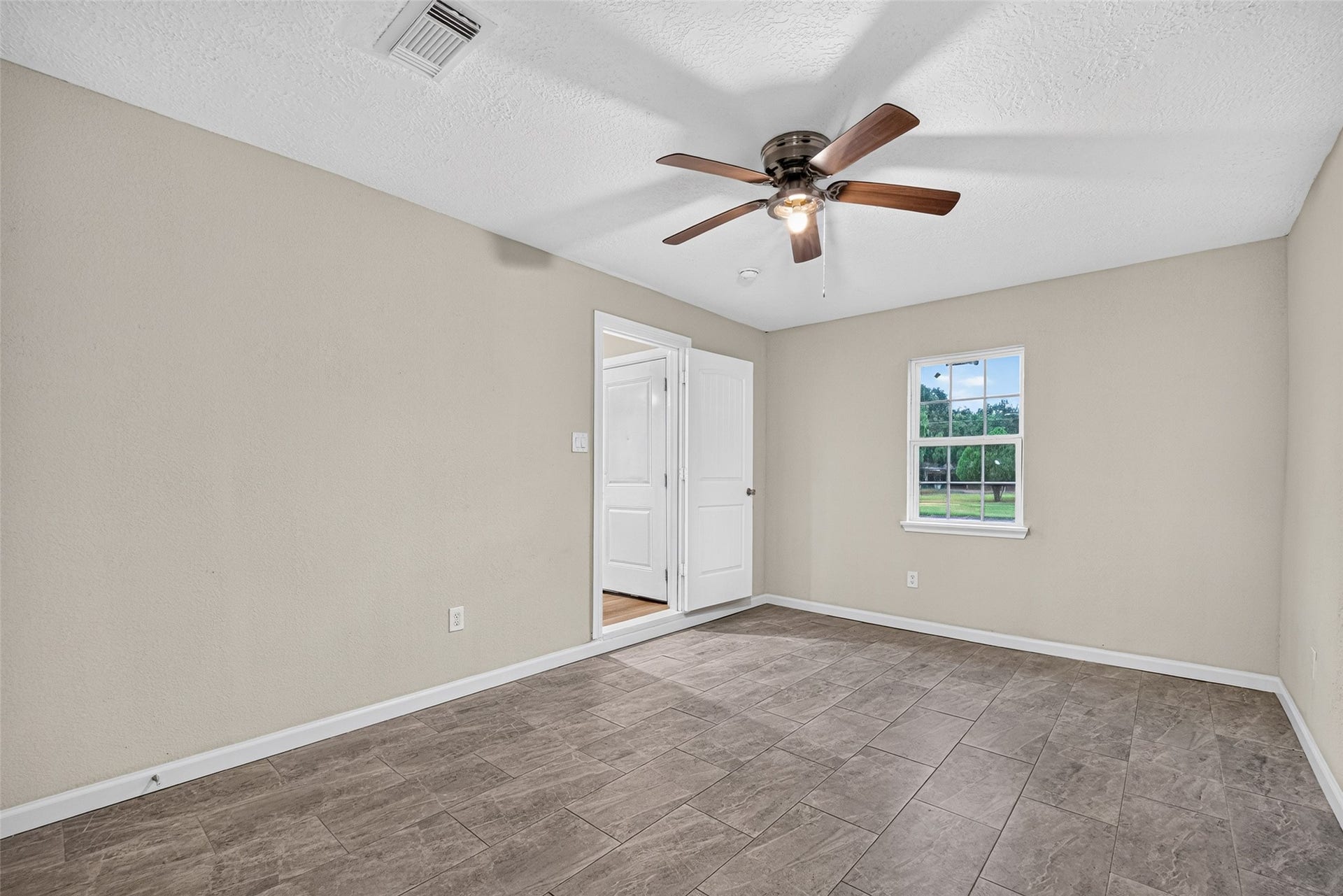 Primary bedroom completer with ensuite and ceiling fan.