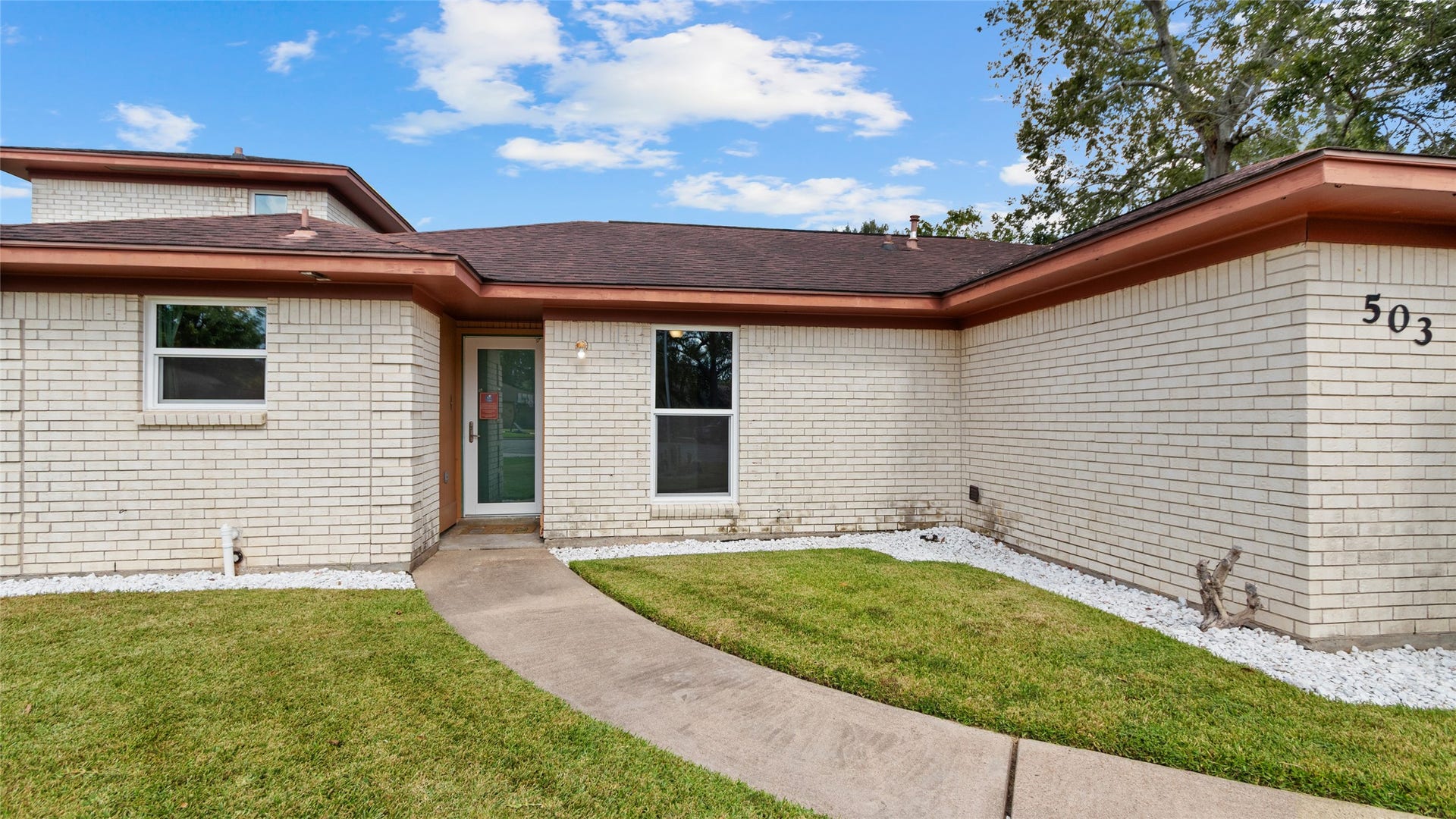 503 Allen Court, Alvin, TX 77511 Closer exterior view highlights the home's classic brick exterior, updated windows, curved walkway, and low-maintenance landscaping leading to the front entry.