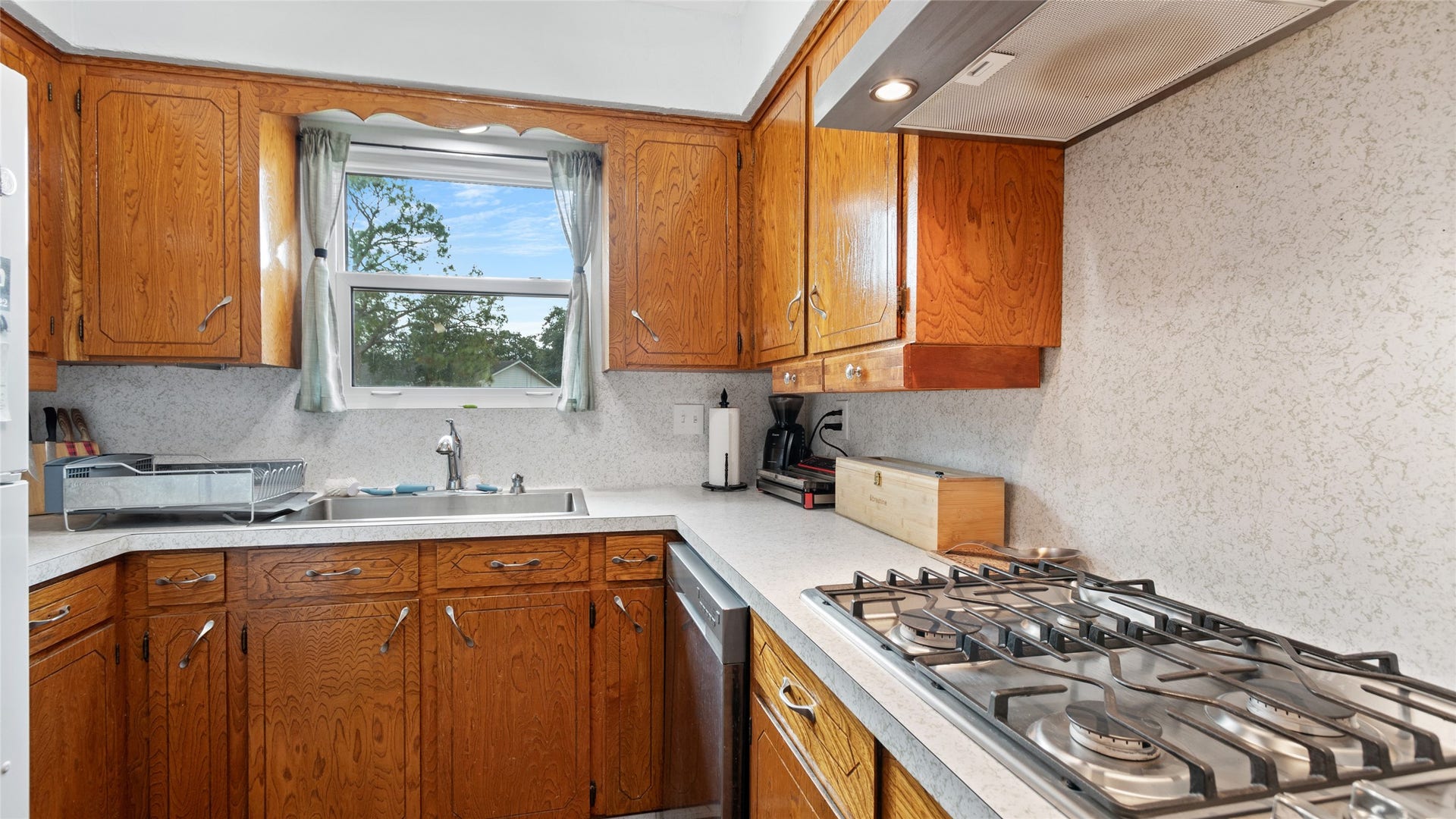 503 Allen Court, Alvin, TX 77511 Kitchen features abundant cabinetry and counter space, a gas cooktop, stainless steel dishwasher, and a window above the sink providing natural light.