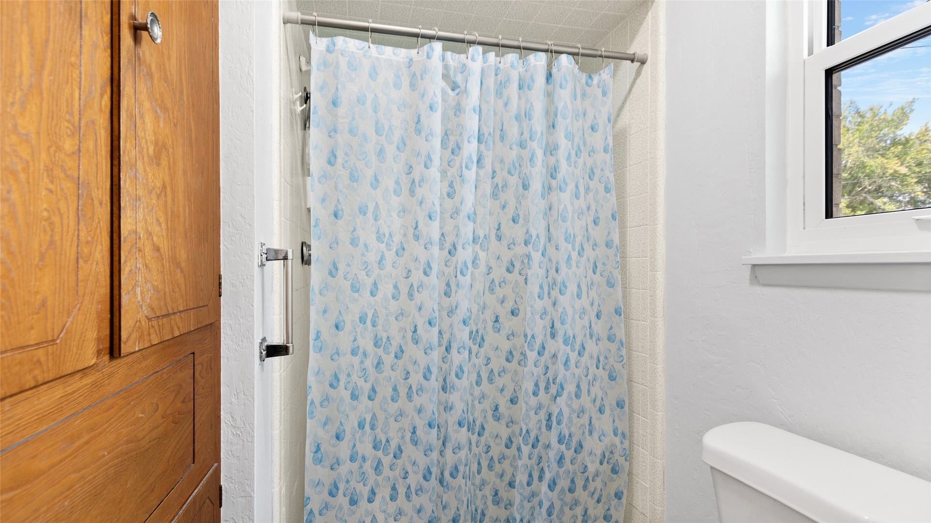 503 Allen Court, Alvin, TX 77511 Tub/shower combination with tiled surround and a nearby window bringing natural light into the full bathroom.
