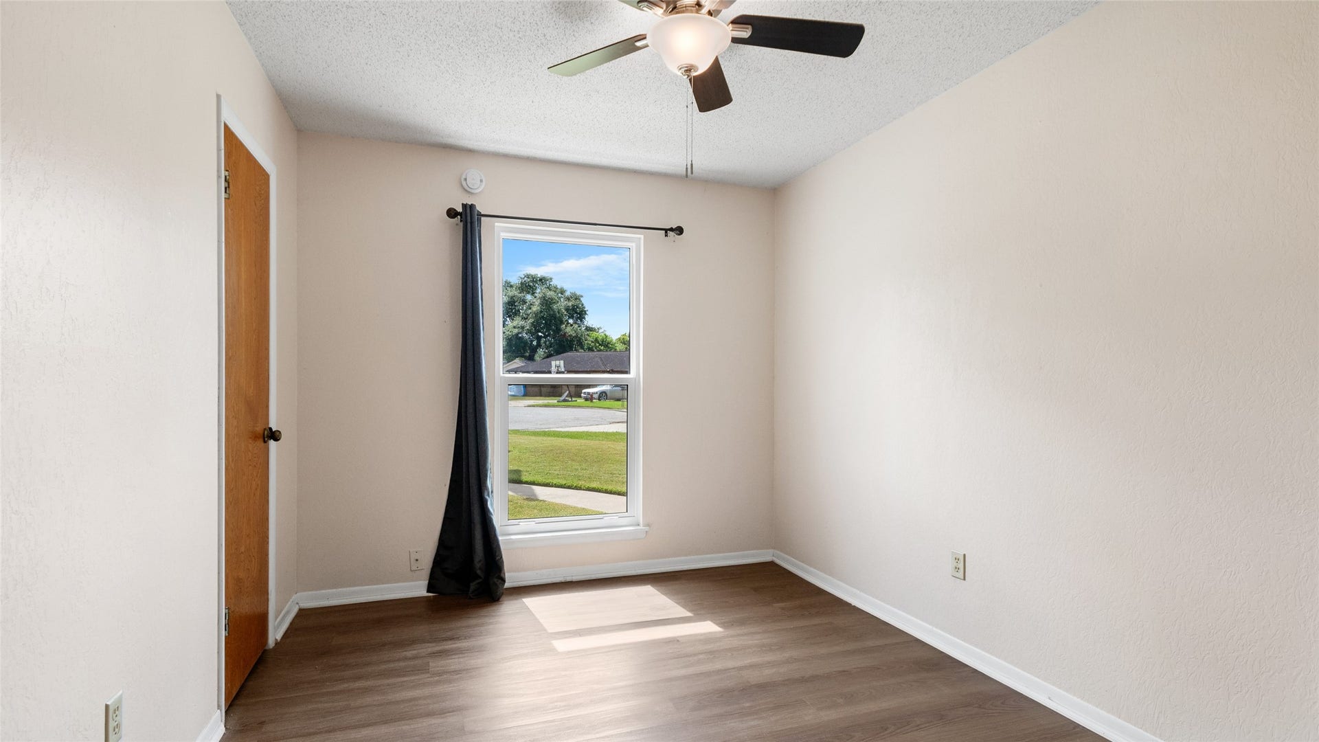 503 Allen Court, Alvin, TX 77511 Bright secondary bedroom with wood-look flooring, ceiling fan, closet, and a large window providing abundant natural light.