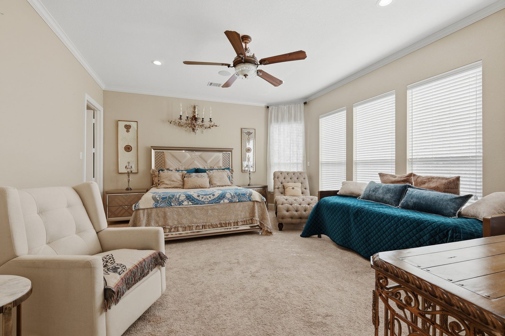 Privately situated on the first floor, this expansive primary suite offers a serene retreat with refined elegance and exceptional comfort. Generous proportions allow for both sleeping and sitting areas, while soft neutral tones, crown molding, and plush carpeting create a warm, inviting ambiance. Large windows fill the space with natural light, enhancing the airy feel and highlighting the rooms thoughtful design