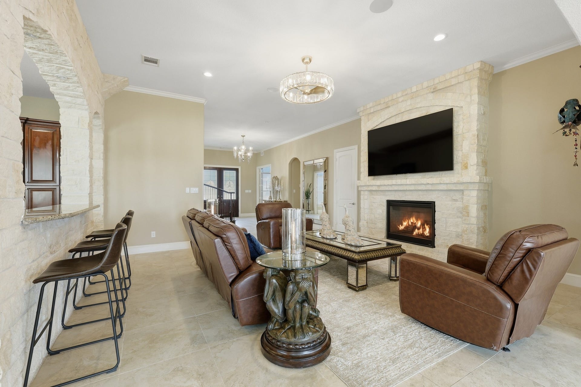 An impressive gathering space defined by a floor-to-ceiling stone fireplace that anchors the room with warmth and architectural elegance. The open-concept design flows seamlessly into the kitchen and adjacent areas, creating a cohesive environment ideal for both entertaining and everyday living.