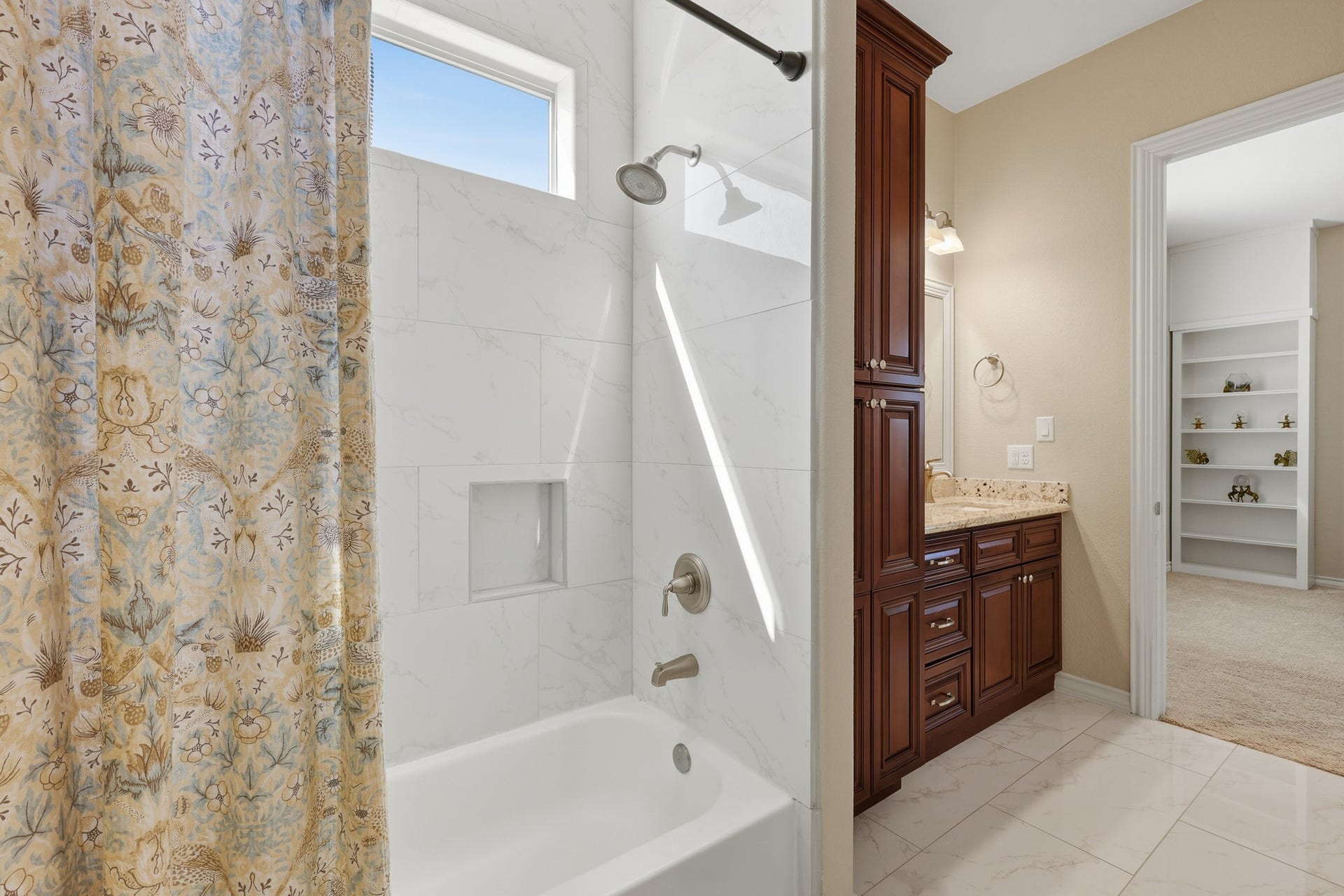 The en suite bath features custom cherry wood cabinetry topped with granite countertops, beautifully complemented by marble-inspired tile surrounding the tub and shower for a timeless, refined finish. A large walk-in closet provides generous storage and organization, completing this thoughtfully designed upper-level sanctuary that blends privacy, sophistication, and everyday luxury.