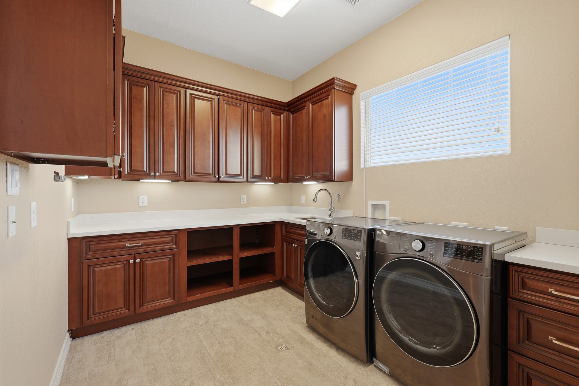 Designed with both beauty and efficiency in mind, the upstairs utility room features custom cherry wood cabinetry, expansive countertops for folding and organization, and a built-in utility sink. Abundant storage and thoughtful layout elevate this space into a refined and highly functional extension of the home.