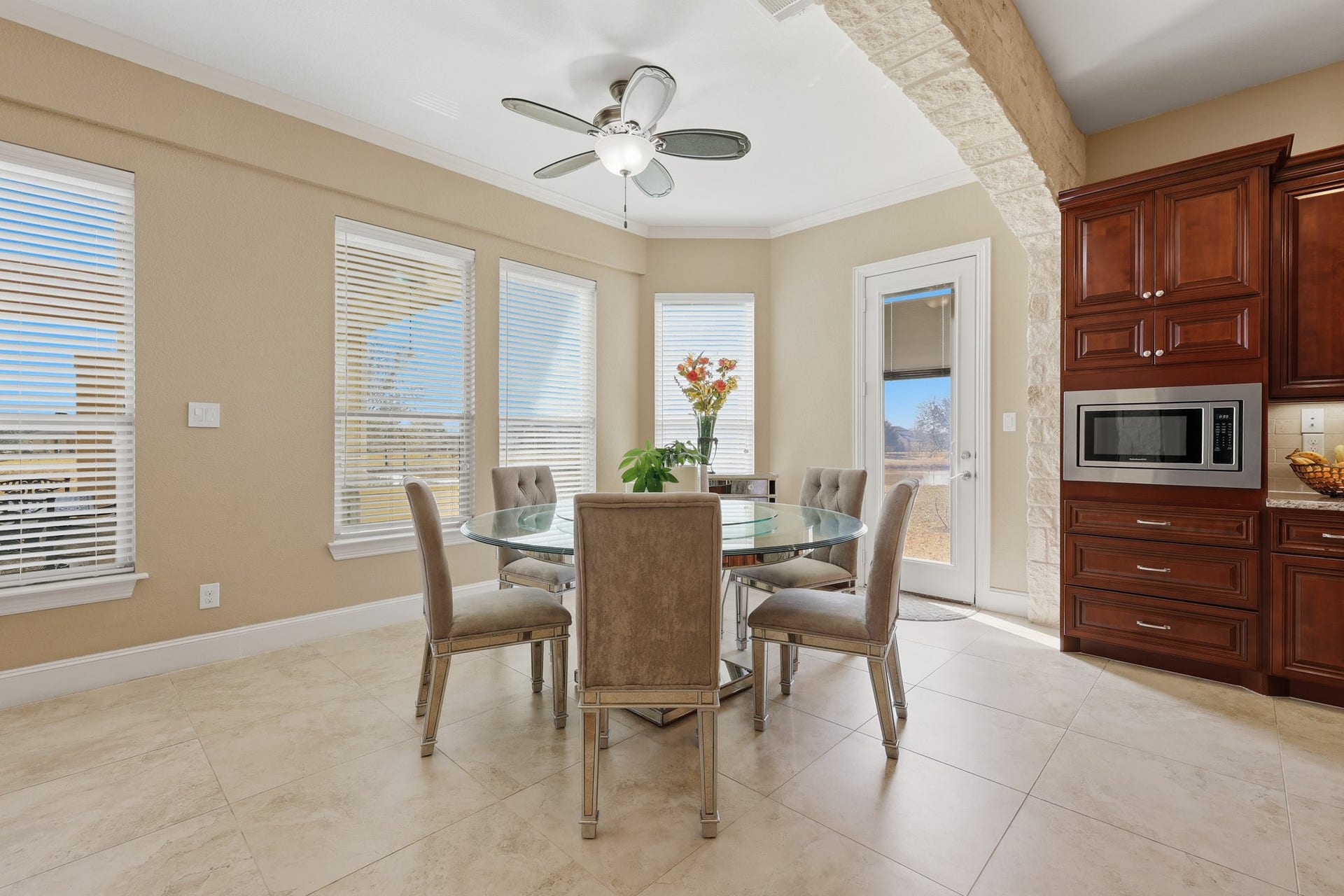 Bathed in natural light from surrounding windows, this elegant breakfast area offers a serene setting for morning coffee or dining. The space overlooks the beautifully landscaped backyard and enjoys tranquil views of the pond beyond, creating a peaceful waterfront backdrop visible right from the table. The direct outdoor access enhances the airy, open feel. Seamlessly connected to the kitchen, this inviting breakfast area blends everyday convenience with scenic luxury.