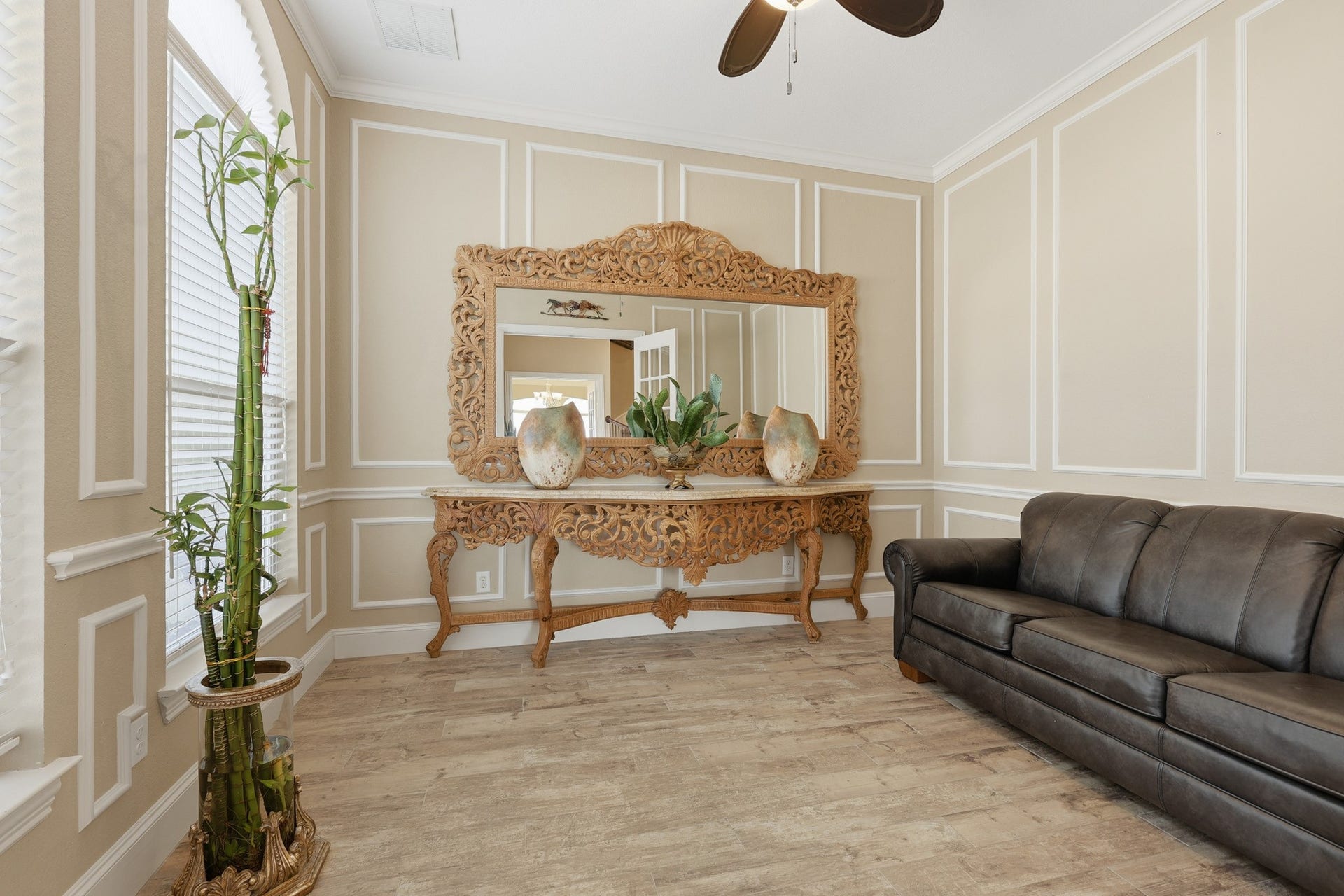 Bathed in natural light from striking arched windows, this refined formal living space offers both elegance and versatility. Classic wall moldings and soaring ceilings provide architectural distinction, while the soft, neutral tones create a serene and sophisticated atmosphere.