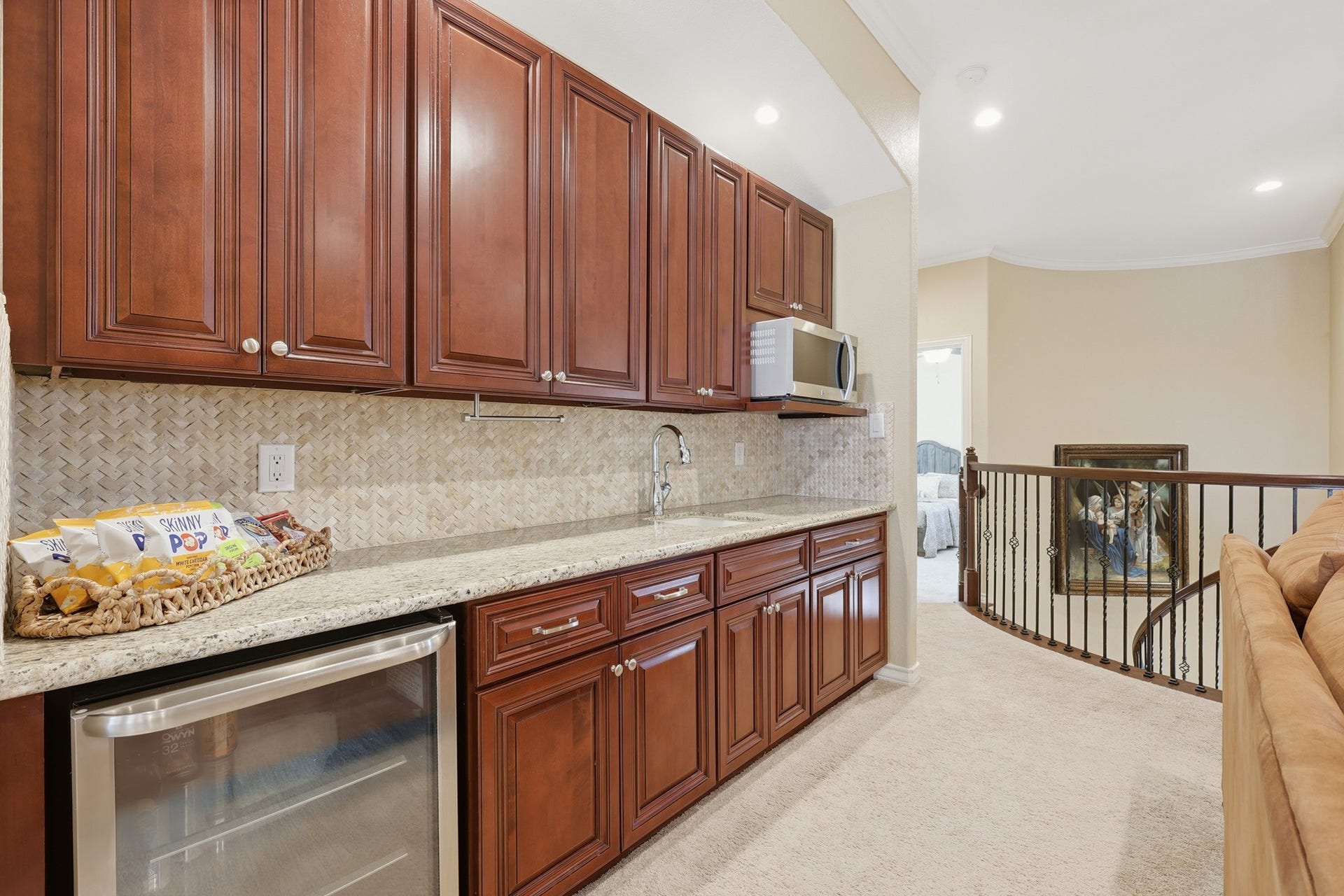 A built-in refreshment bar with custom cherry wood cabinetry, granite countertops, stainless steel sink and microwave and a beverage cooler enhances the space for effortless entertaining.