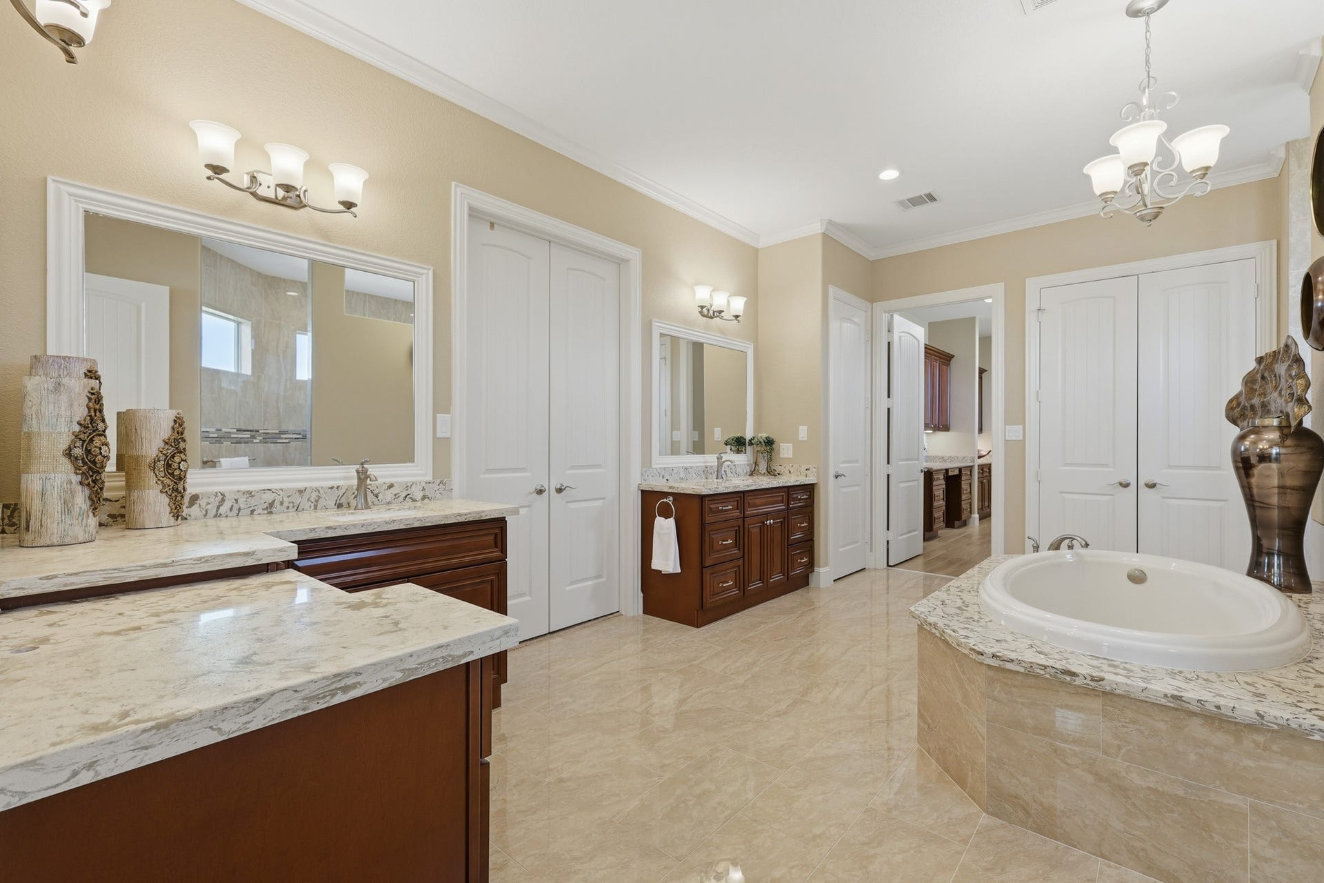 Dual vanities with abundant cabinetry and expansive mirrors provide both sophistication and functionality, all complemented by refined lighting and timeless materials throughout.

Completing the suite is an impressive double-wide walk-in closet, outfitted with custom built-ins for optimal organization and storage. Designed to accommodate extensive wardrobe needs with ease, this beautifully appointed space blends practicality with upscale appealoffering a truly luxurious primary retreat .
