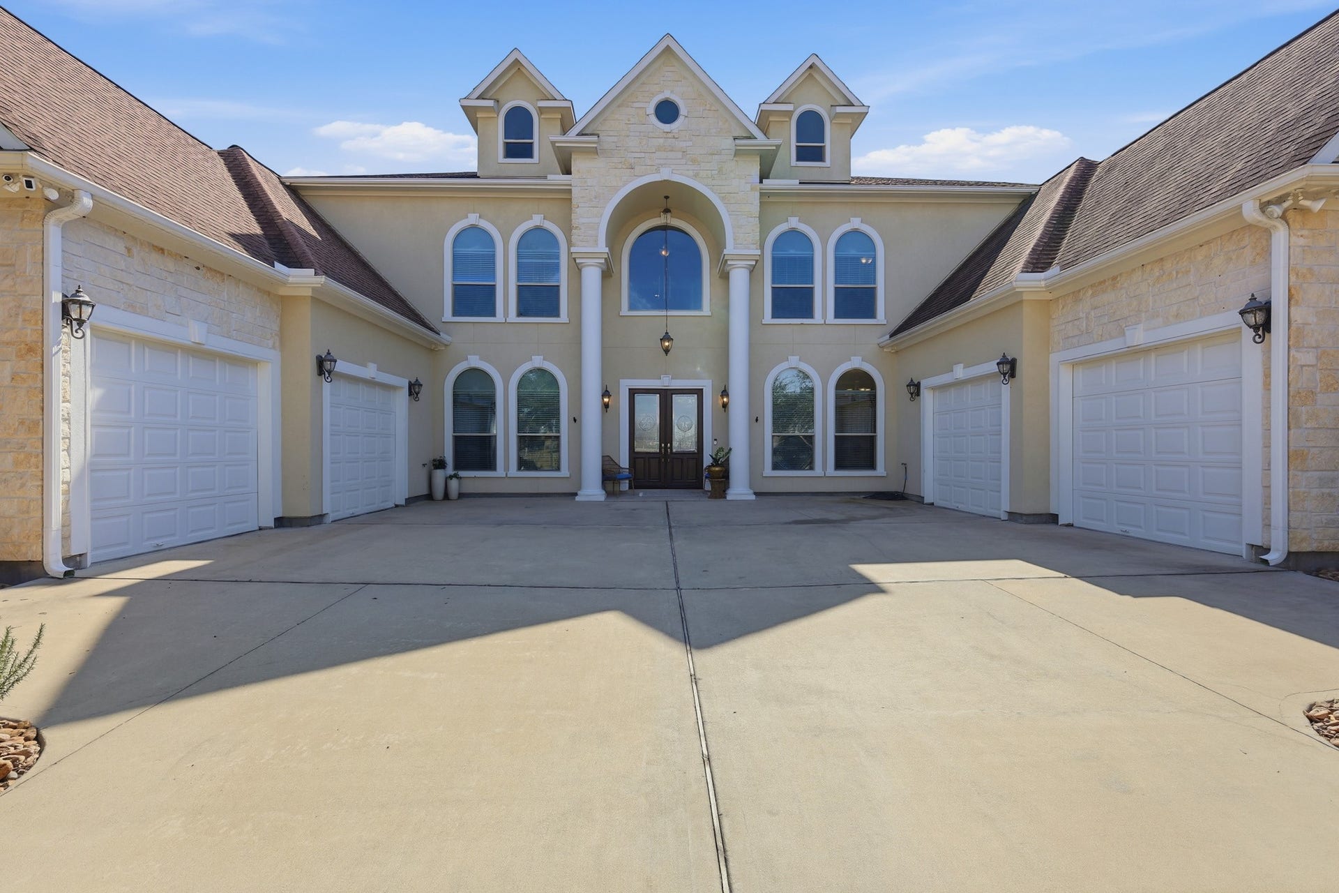 The impressive two-story entrance is highlighted by soaring columns, a dramatic arched window, and double glass doors that set the tone for the luxury found throughout the home. Architectural details and natural light create a warm yet sophisticated welcome.