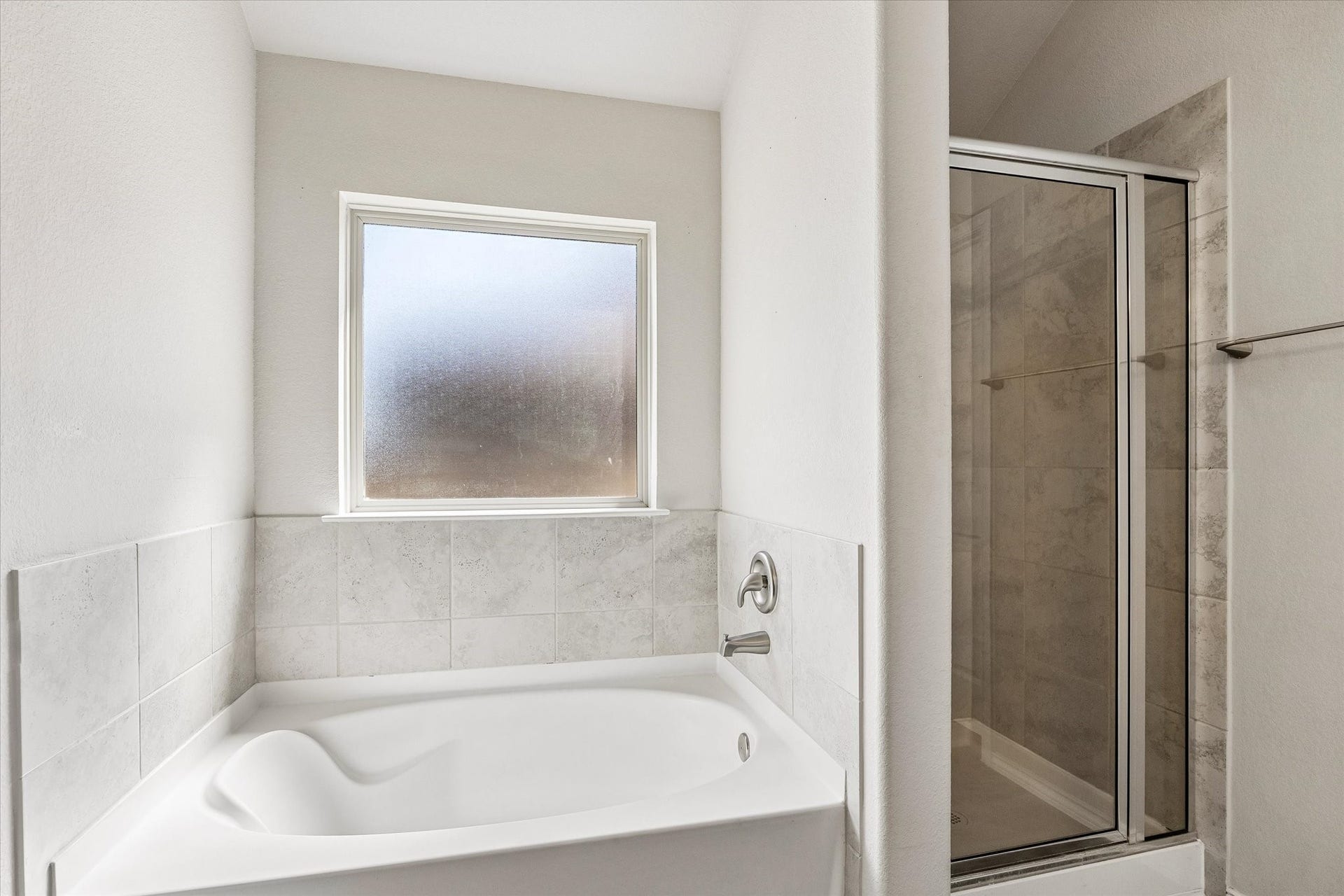 111 Valiant Ridge Trail, Magnolia, TX 77354 Unwind in the soaking tub or enjoy the separate glass-enclosed shower. Tile surrounds and a privacy window complete this inviting bath.