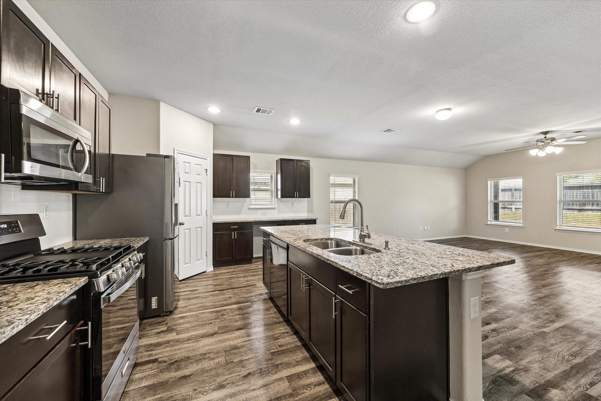 111 Valiant Ridge Trail, Magnolia, TX 77354 The kitchen features granite countertops, rich-toned cabinetry, stainless steel appliances and a generous island with seating space. An open view into the living area keeps everyone connected.