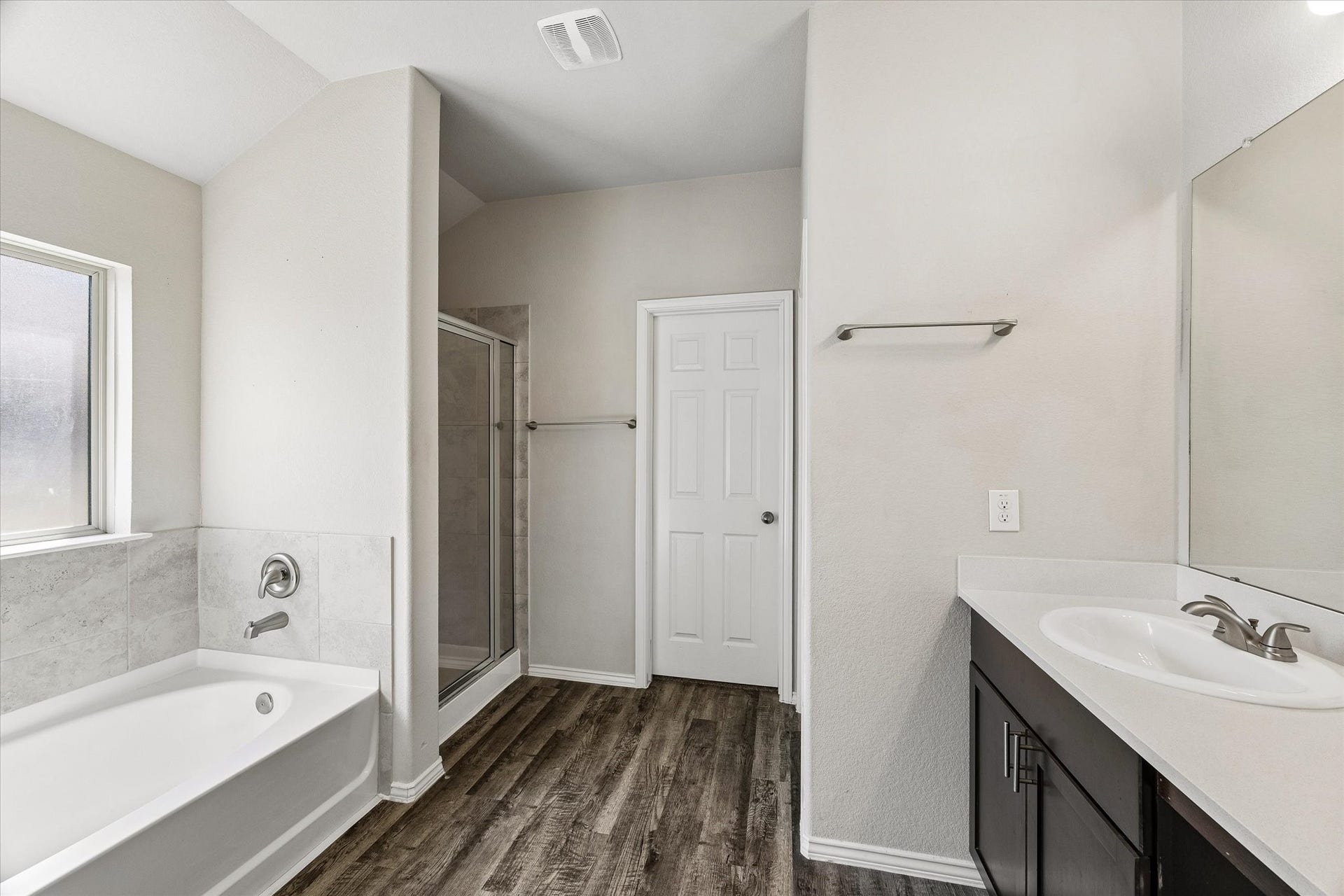 111 Valiant Ridge Trail, Magnolia, TX 77354 The primary bathroom features a soaking tub, separate shower and a vanity with cabinet storage. Wood-look flooring adds warmth to the space.