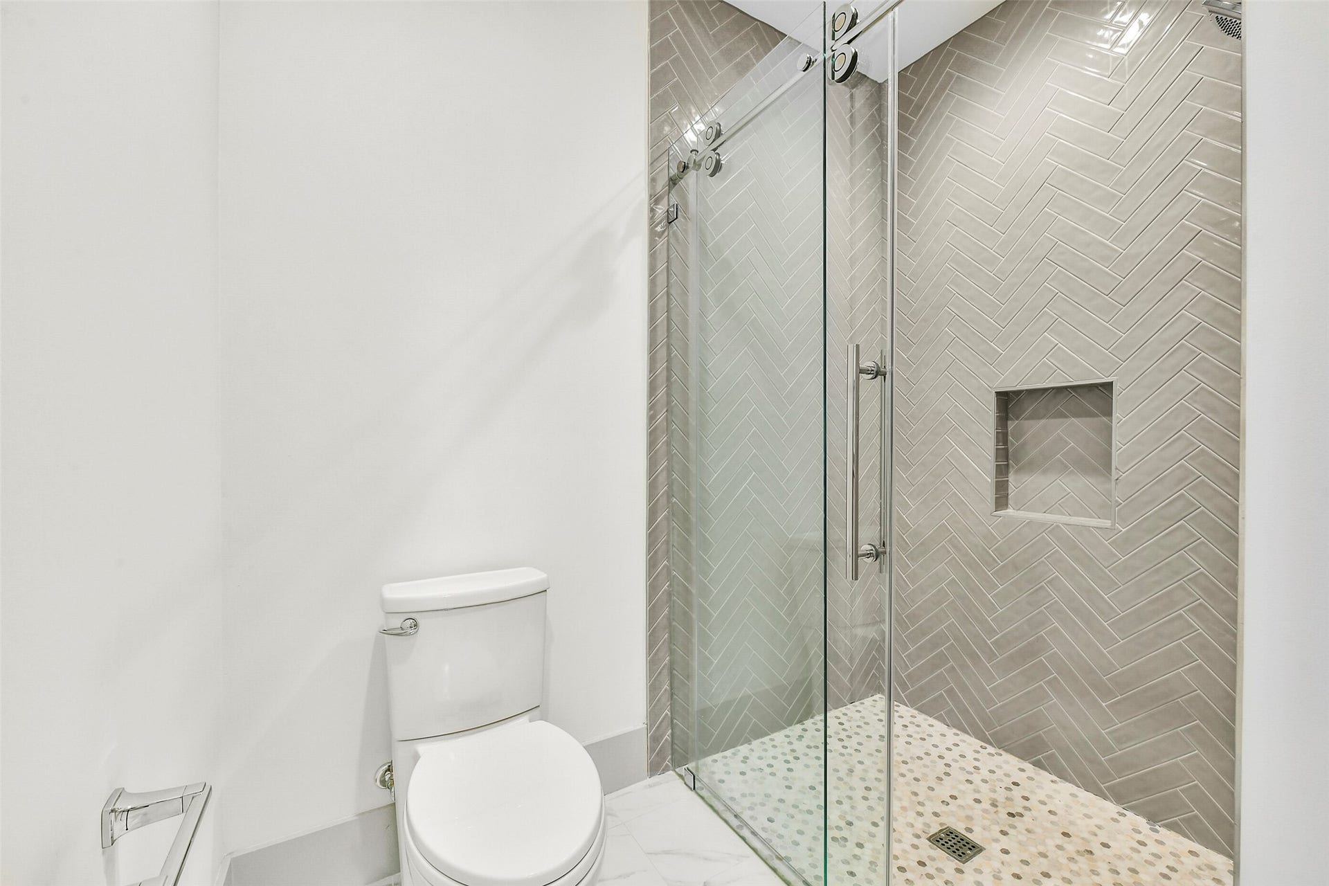 Chevron tile being installed in the glass enclosed walk-in shower off the secondary bedroom.