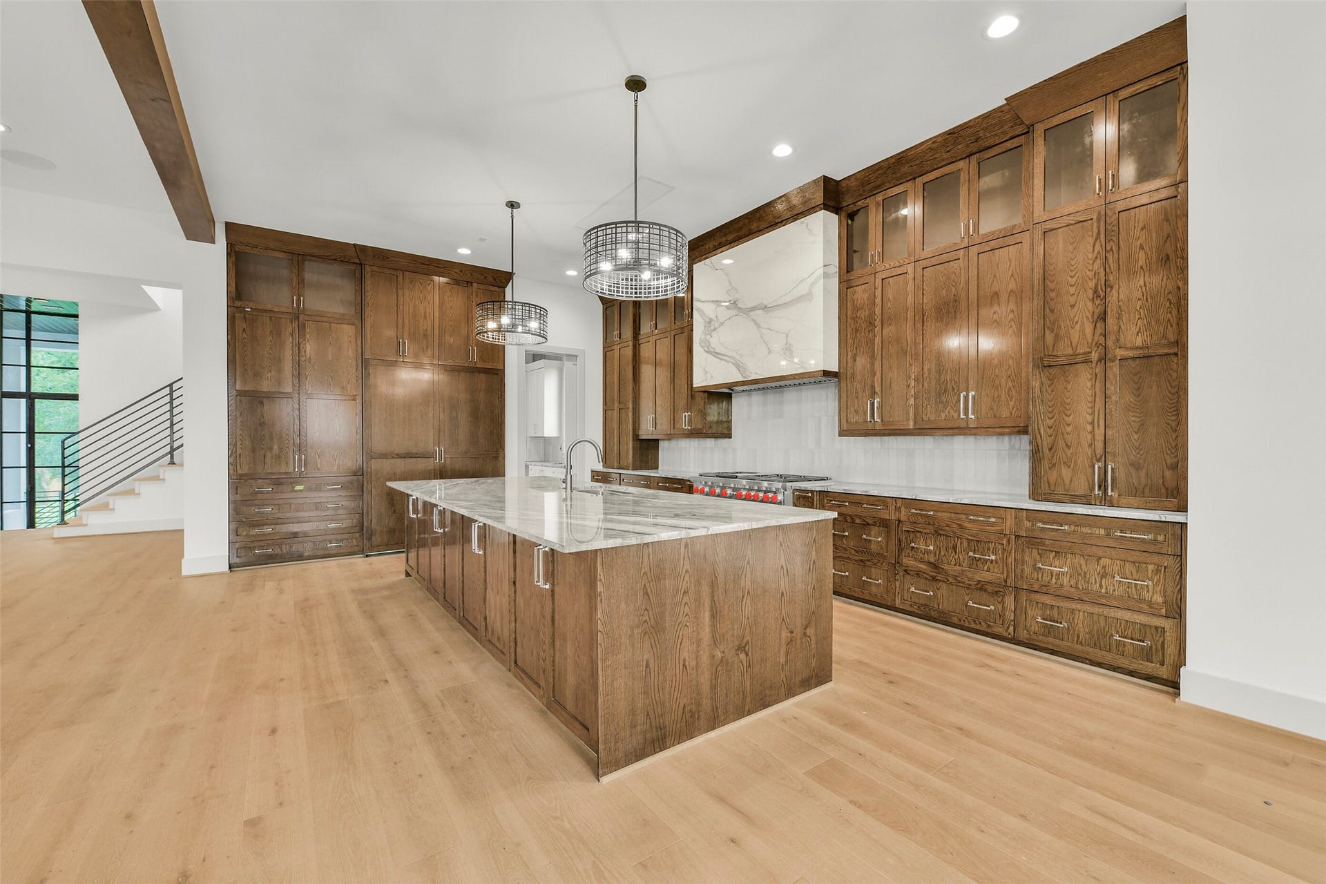 The kitchen features custom cabinets with island storage as well as glass front upper cabinets. The carefully curated tile and quartzite counter tops accent the space. The scullery kitchen and pantry space are located through the pocket door to the right of the built-in Thermadore side by side refrigerator & freezer.