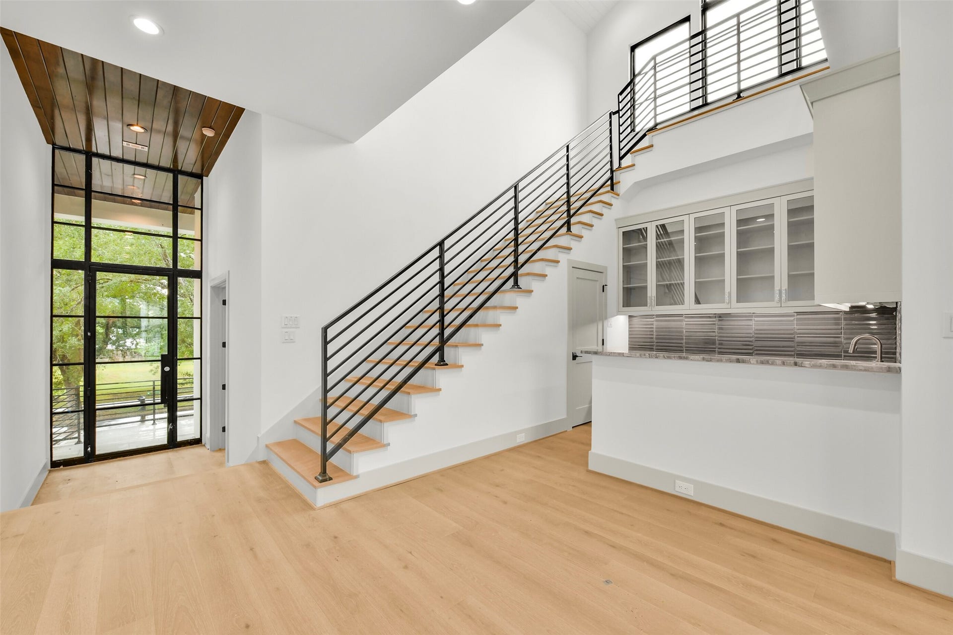Once inside, you will find fourteen-foot ceilings at the front door into an entry space offering access to the study with a full bath. The wet bar fits perfectly in the center of the staircase. It includes a large sink, beverage refrigerator, and ice maker. Quartzite countertops, porcelain backsplash and glass front cabinets complete the space. There is a large storage closet under the stairs.
