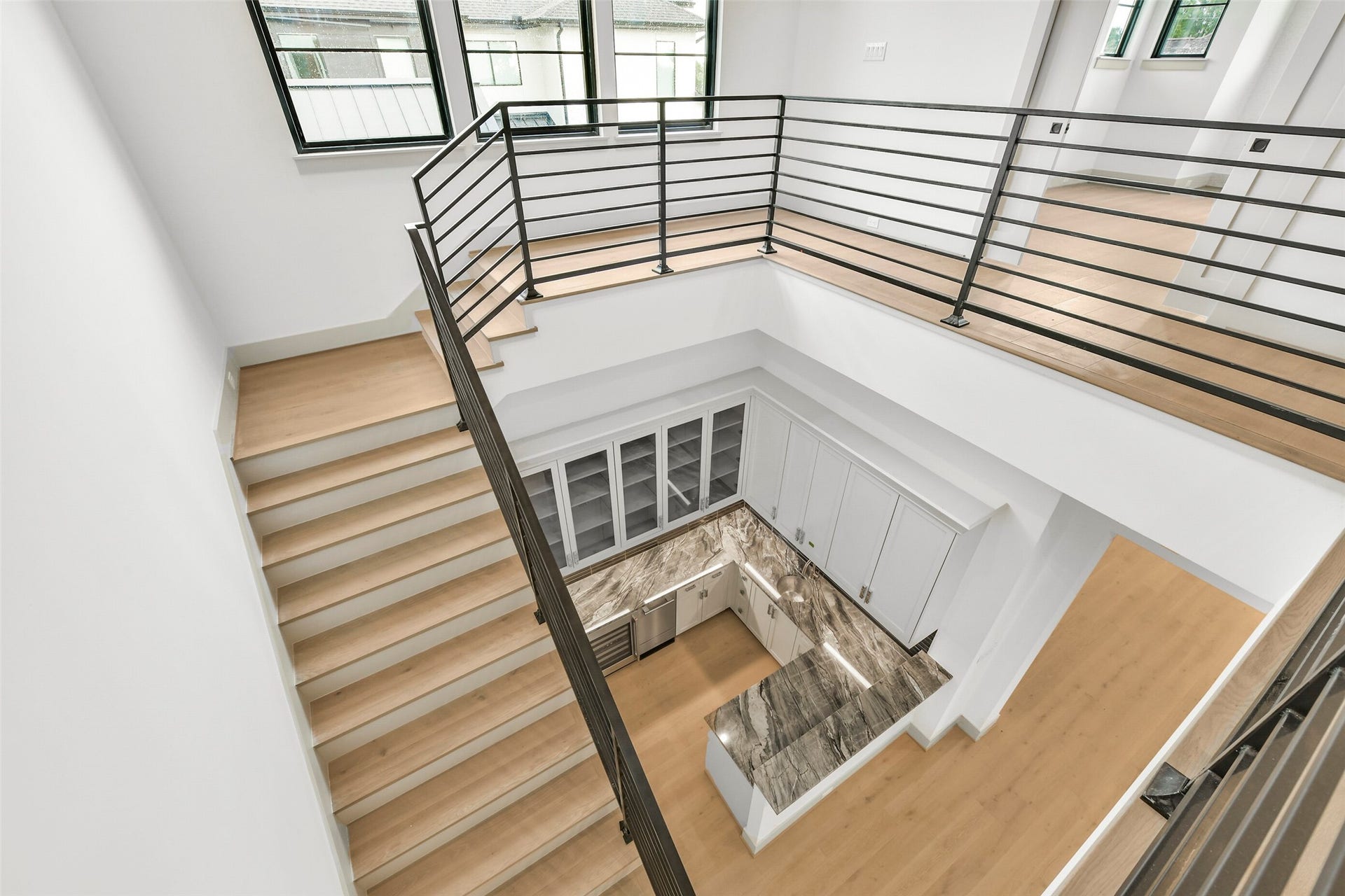 The amazing staircase features high windows and a cathedral ceiling with tongue and groove wood finish allowing light to flow into the wet bar and entry below.