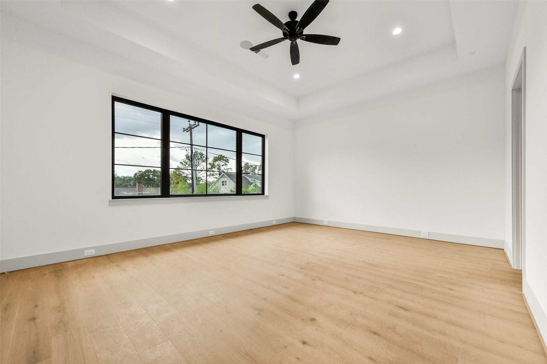 The primary suite is located on the first floor with elevated ceilings and large windows overlooking the backyard.