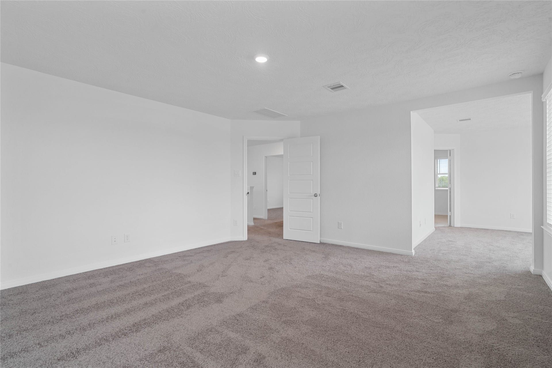 This spacious sitting room, just off the primary bedroom, is perfect for a reading nook, workout space, or a home office. It features large windows with privacy blinds, recessed lighting and carpet flooring!