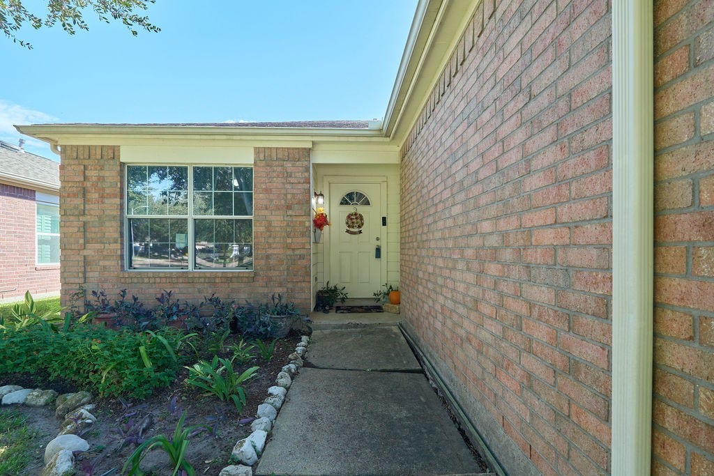 5934 Spring Sunrise Drive, Richmond, TX 77407 A warm welcome awaits! A charming brick-accented entrance creates an inviting first impression.