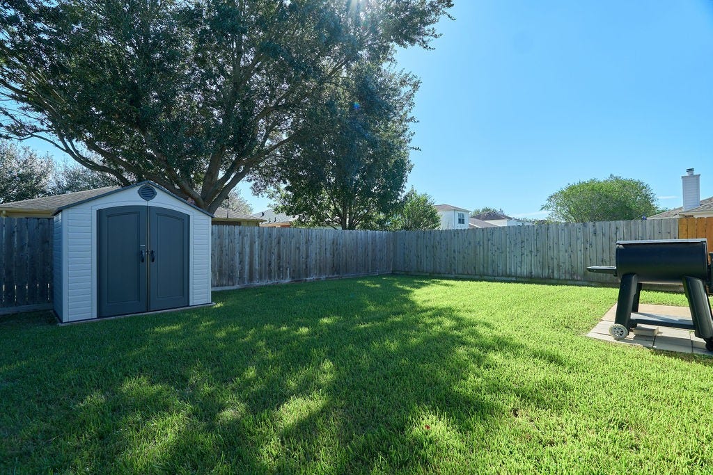 5934 Spring Sunrise Drive, Richmond, TX 77407 Room to breathe, play, and unwind! A generous grassy backyard framed by mature trees and open skies.