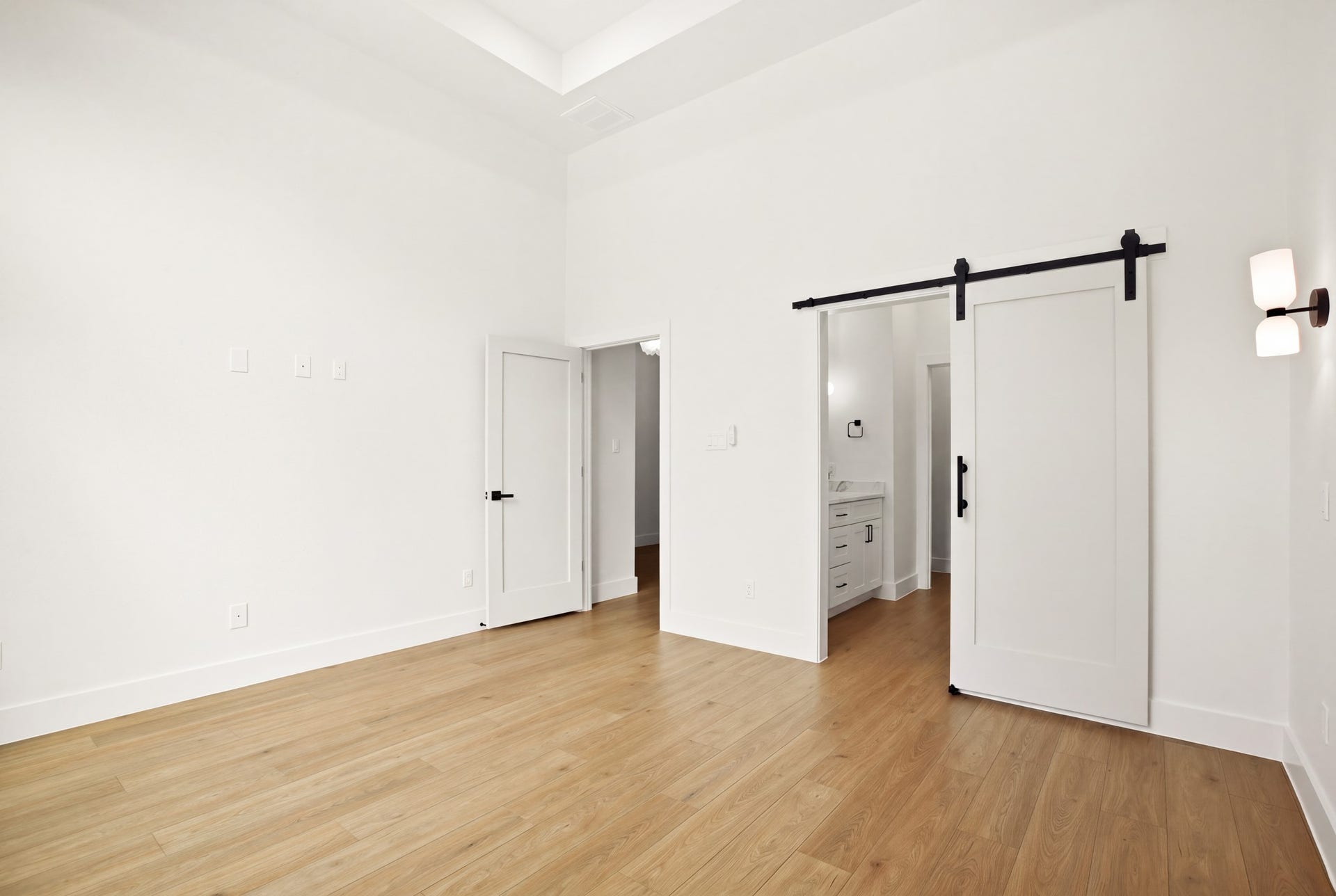 Spacious bedroom with warm flooring and stylish sliding barn doors.