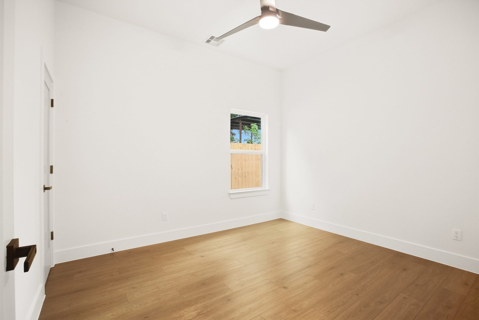 Bright bedroom with warm flooring and a simple, inviting design.
