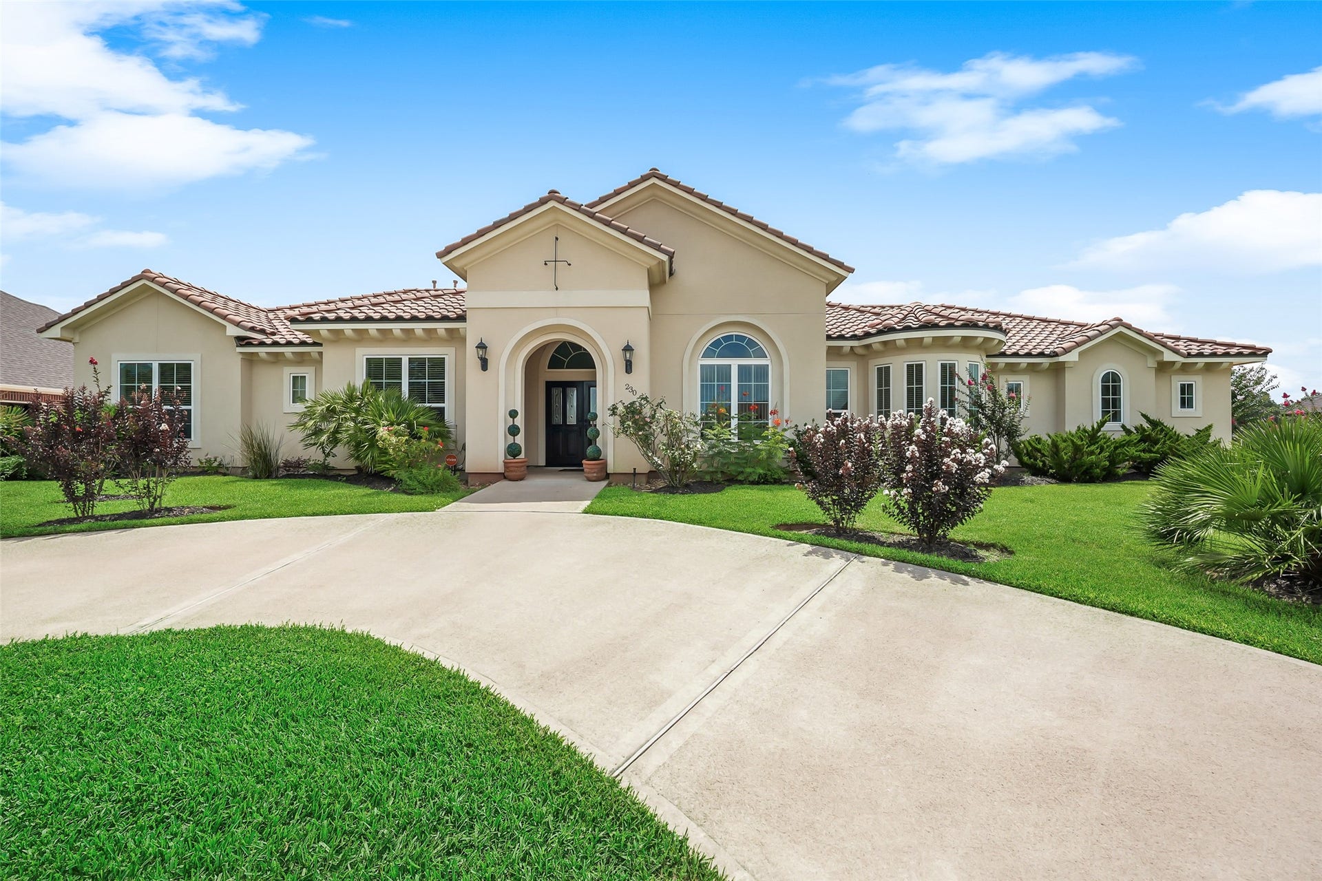 230 Lawrence Marshall Drive, Hempstead, TX 77445 Elegant front elevation featuring a covered entry, tile roof, mature landscaping, and timeless architectural details.