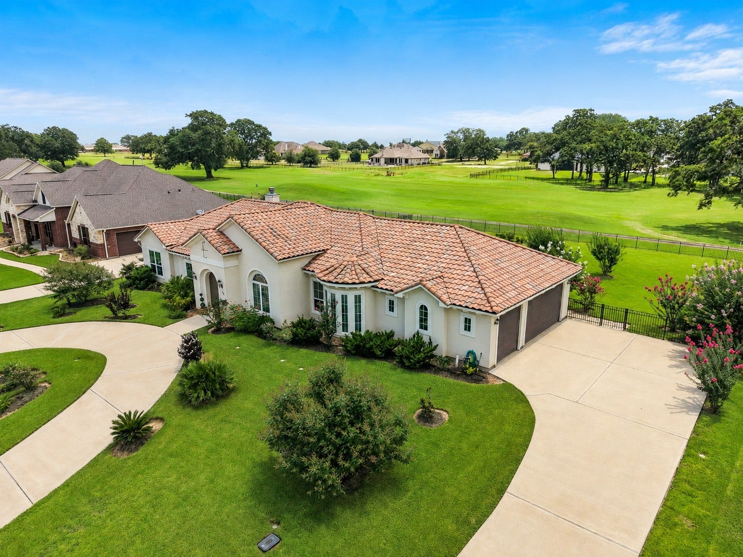 230 Lawrence Marshall Drive, Hempstead, TX 77445 Side aerial view showcasing the home's Mediterranean design, oversized 3-car garage, circular driveway, and picturesque golf course setting.