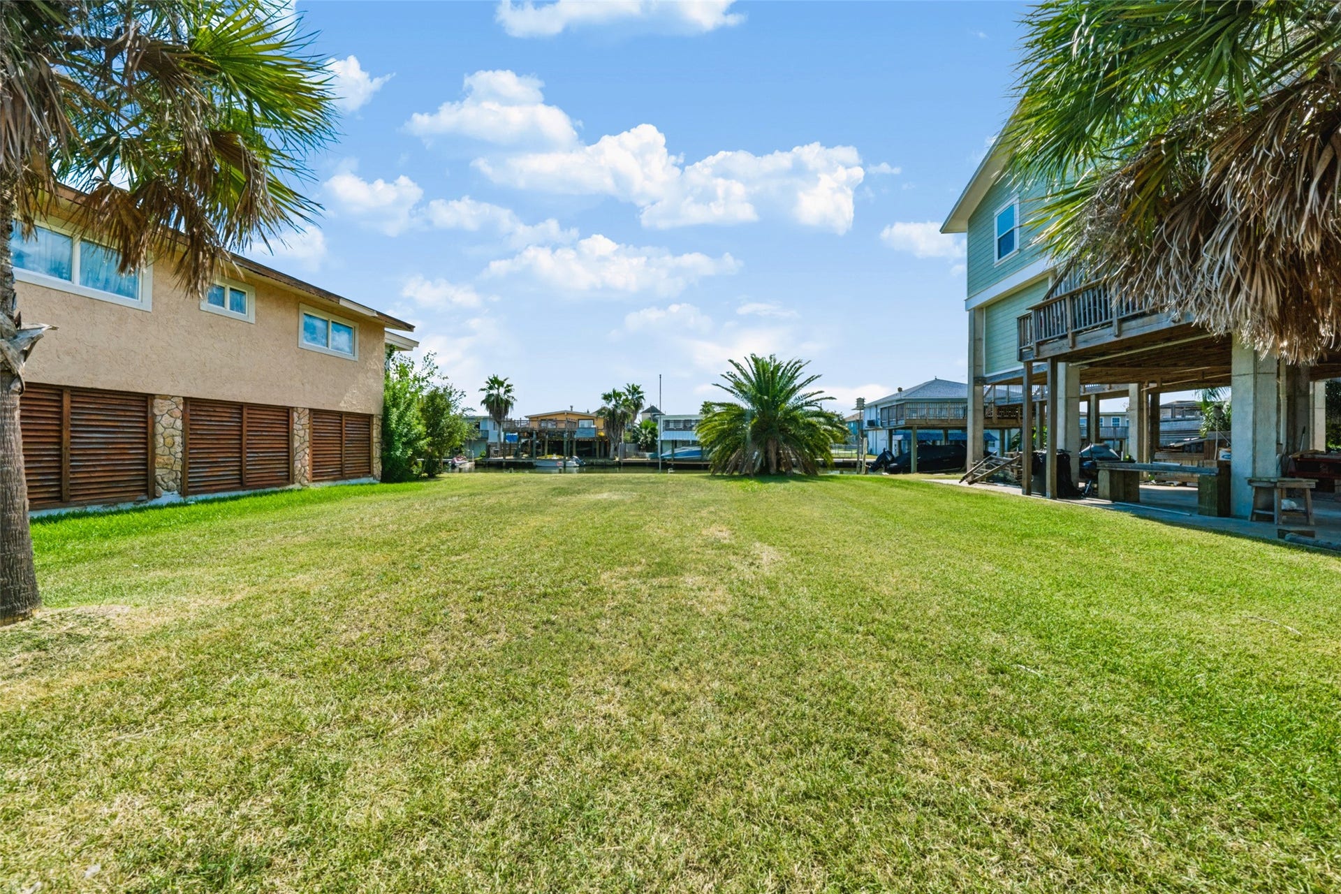 65 Lakeside Drive, Hitchcock, TX 77563 Looking across the lot toward the neighbor's raised home. This gives you a feel for scale and how the homes along here sit with living space up top and parking below. Build the same way and you would have canal views from every room up high.