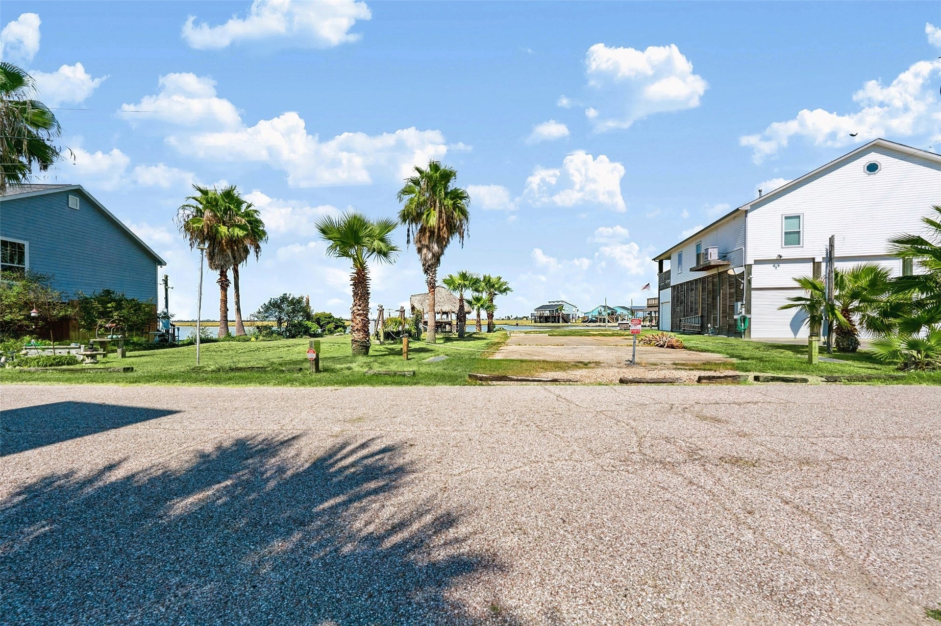65 Lakeside Drive, Hitchcock, TX 77563 Lakeside Drive out front, with the lot's two Sabal palms joining the palms down the street and open ground across the road where the sunsets show up. Easy to picture your front porch here!
