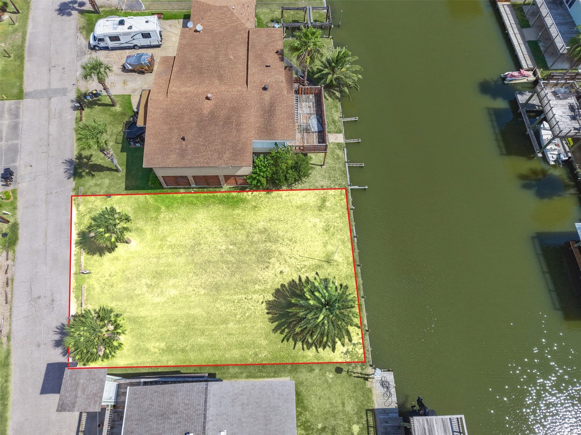 65 Lakeside Drive, Hitchcock, TX 77563 Straight down on the whole lot. A mature Canary Island date palm toward the water, two Sabal palms at the street, open grass between them, the canal on the right and Lakeside Drive on the left. Electric, gas, cable and phone are available, and water comes from Galveston County MUD 12, so the utilities are ready when you are!