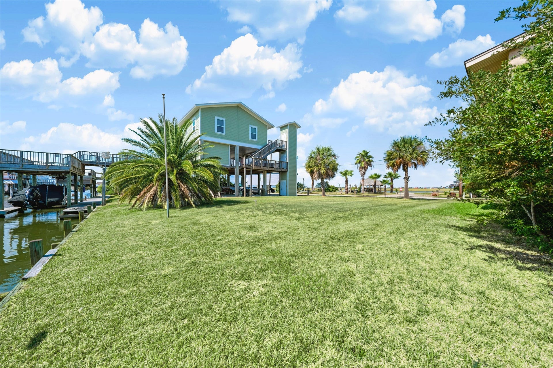 65 Lakeside Drive, Hitchcock, TX 77563 The lot from the front, with the Canary Island date palm at the back and a raised home next door. Room for a driveway and parking under a raised home of your own.