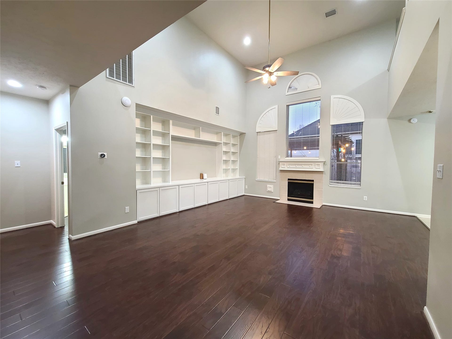 Huge living room features fireplace, lots of shelves, and 2-story high ceiling.