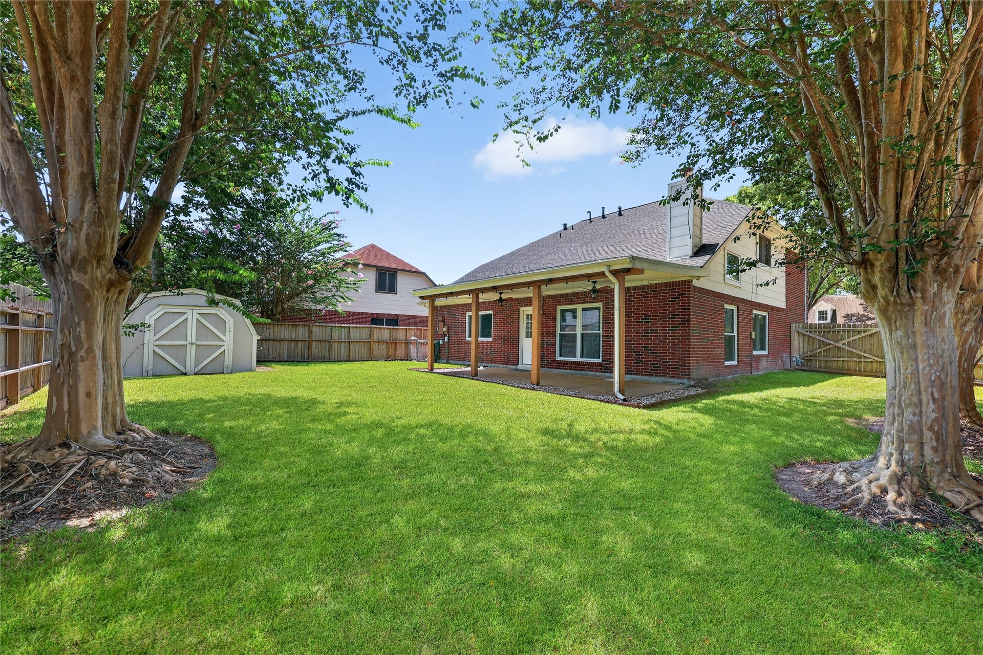 16003 Salton Point Drive, Friendswood, TX 77546 Expansive backyard framed by mature trees and a covered patio, offering space to entertain, play, or unwind.