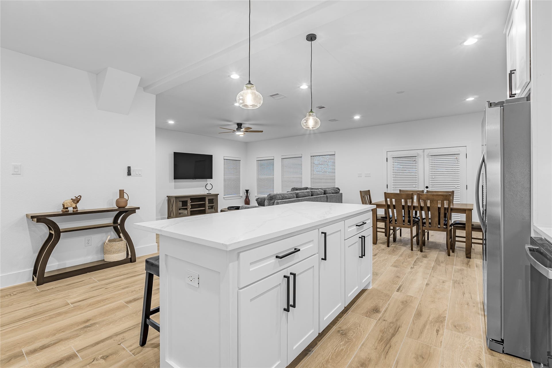 7107 Foster Street, #B, Houston, TX 77021 Open-concept living space with a modern kitchen island, elegant pendant lighting, and seamless flow to the dining and living areas. Actual furniture.