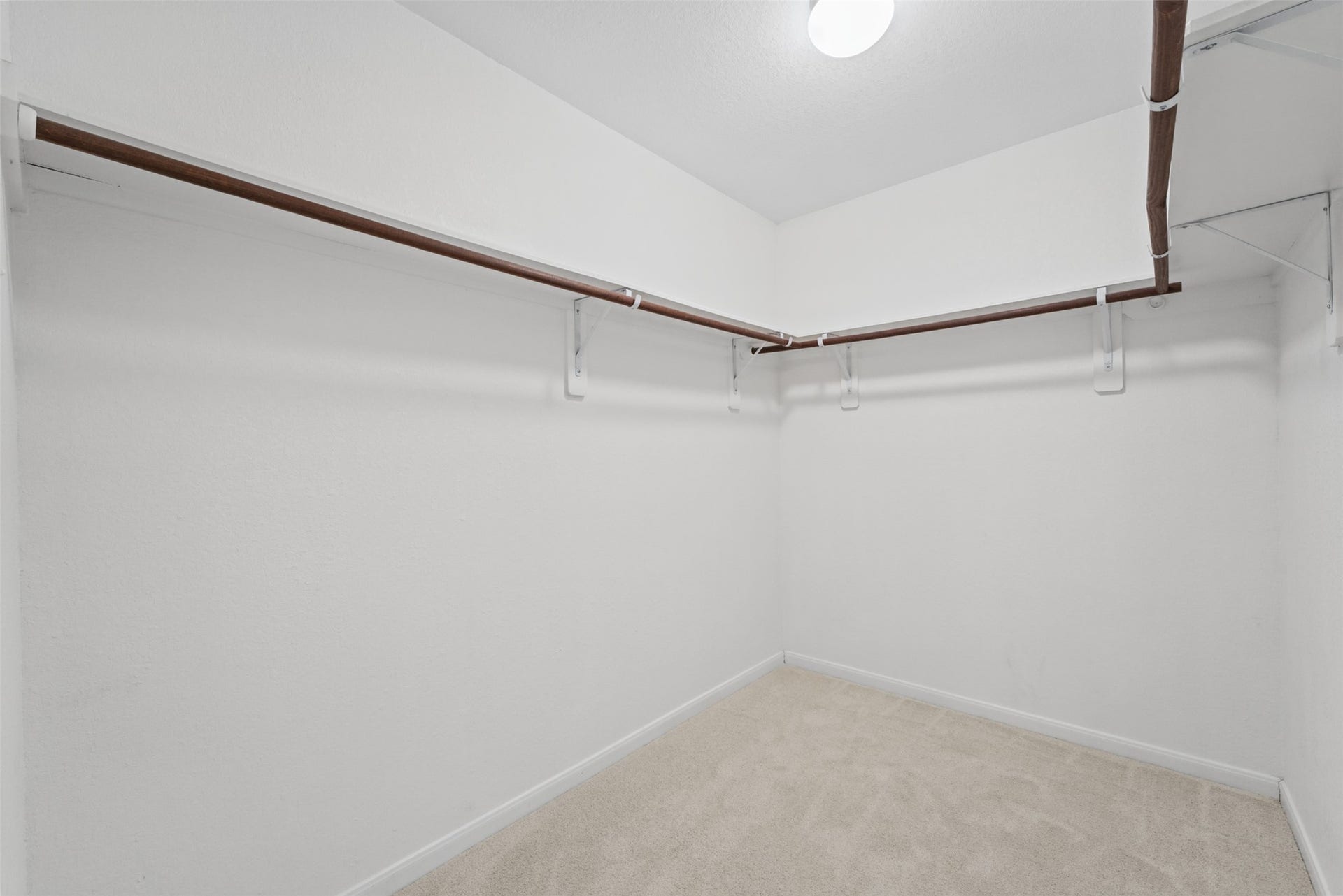 Spacious walk-in closet with ample hanging space and bright lighting.