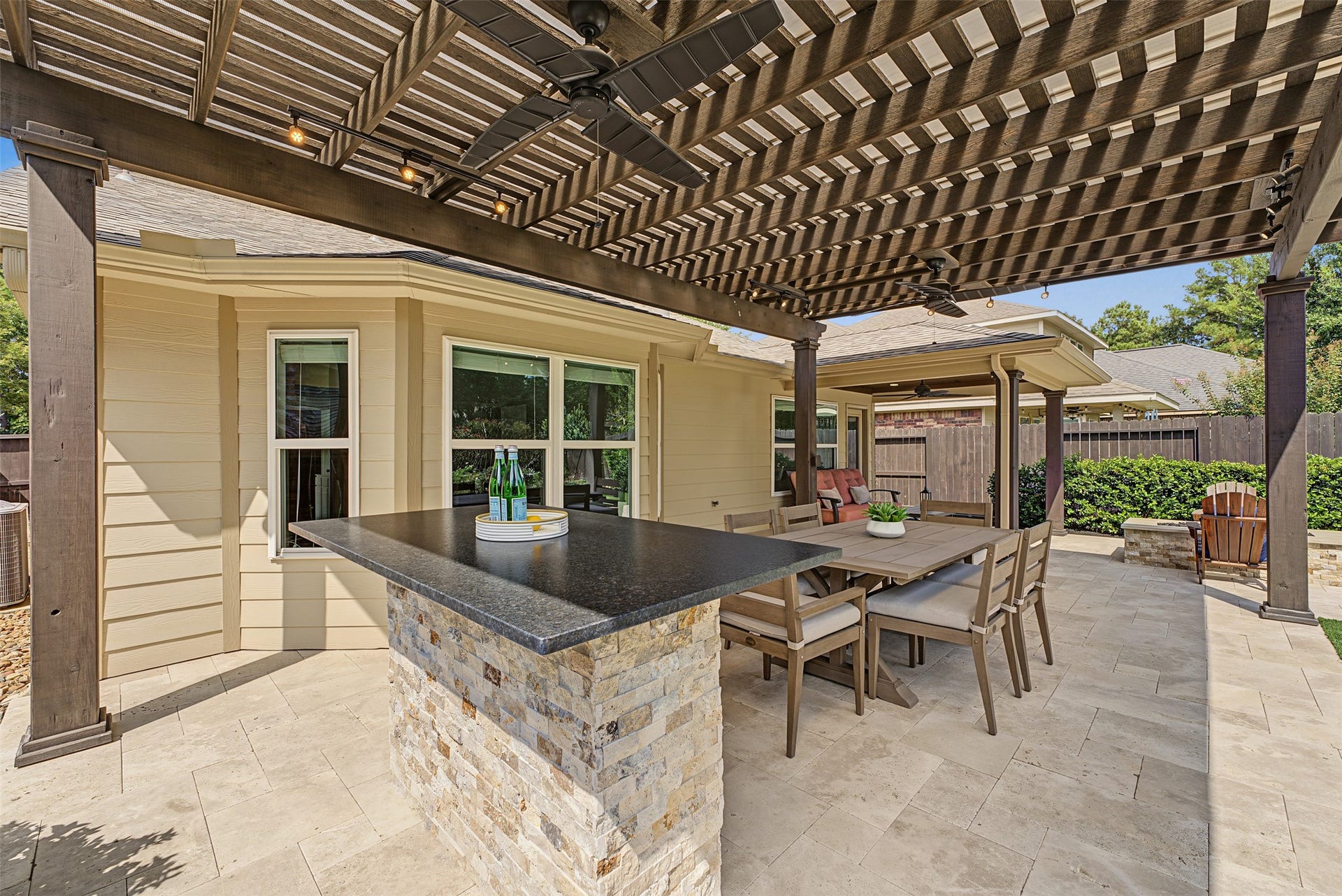 A stylish pergola, built-in bar with stone accents, and a spacious dining area perfect for outdoor entertaining.