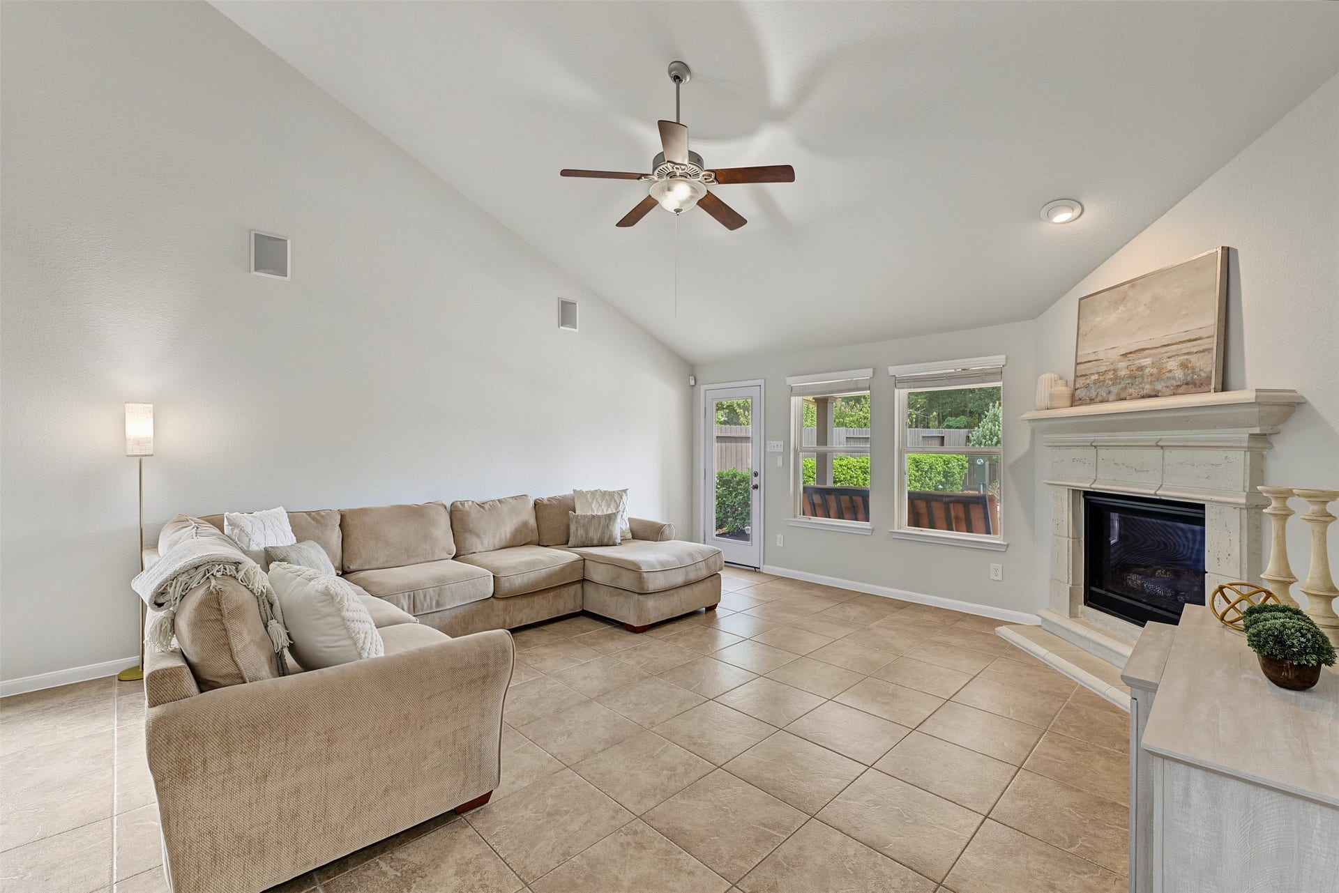 Spacious living room with vaulted ceiling, a cozy fireplace, and abundant natural light from large windows.