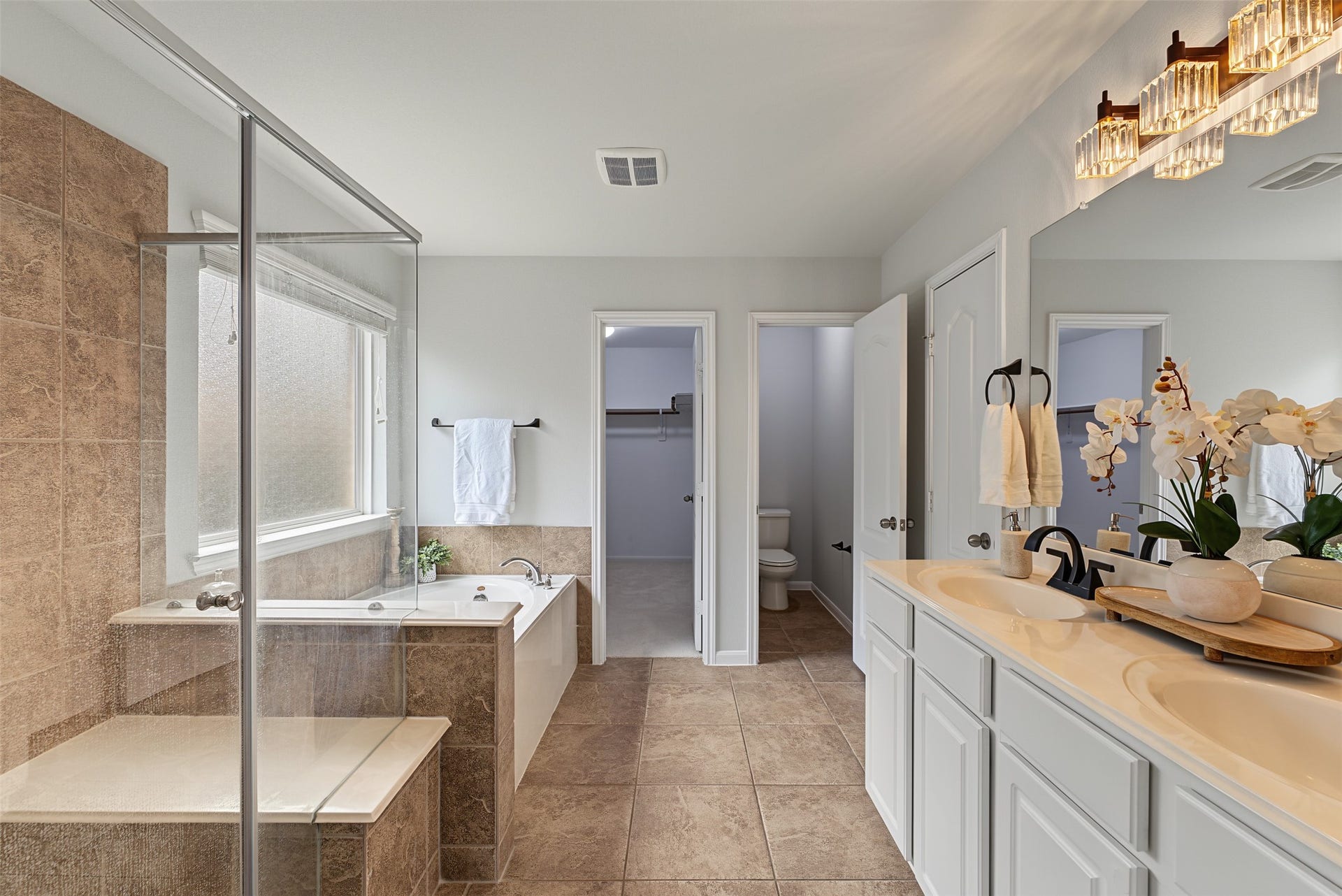 Elegant bathroom featuring a spacious walk-in shower, luxurious soaking tub, and double vanity, complemented by stylish lighting and neutral tones.