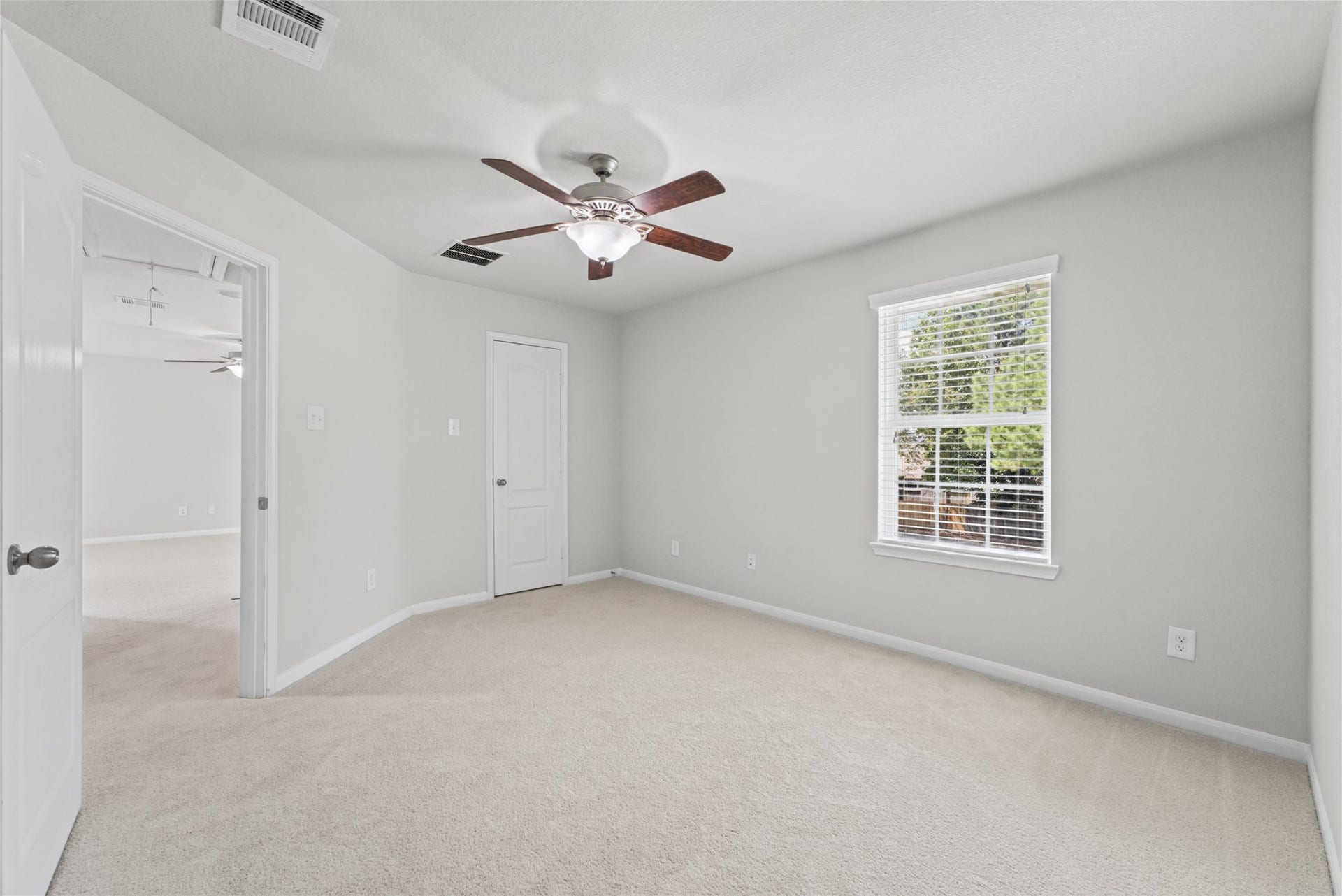 Bright and inviting secondary bedroom with new carpeting, a ceiling fan, and a large window offering natural light.