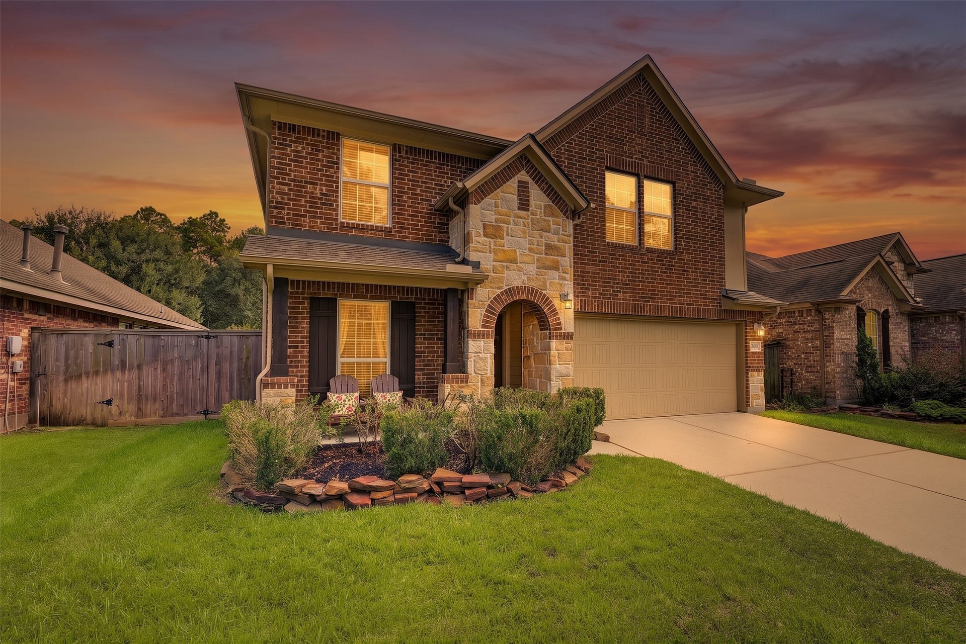 Charming two-story brick home with a warm stone accent facade, inviting front porch, and manicured landscaping.