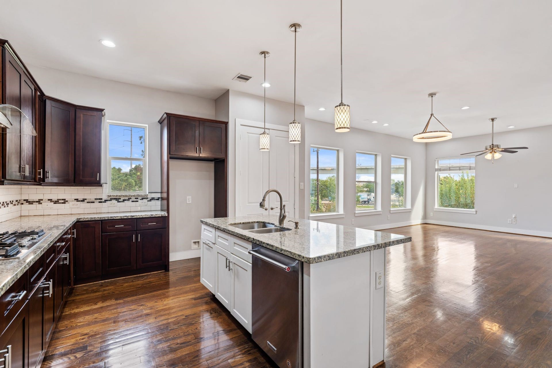 1005 Bingham Street, #5, Houston, TX 77007 Open kitchen with wood cabinetry, granite countertops, a large island with bar seating, and stainless steel appliances.